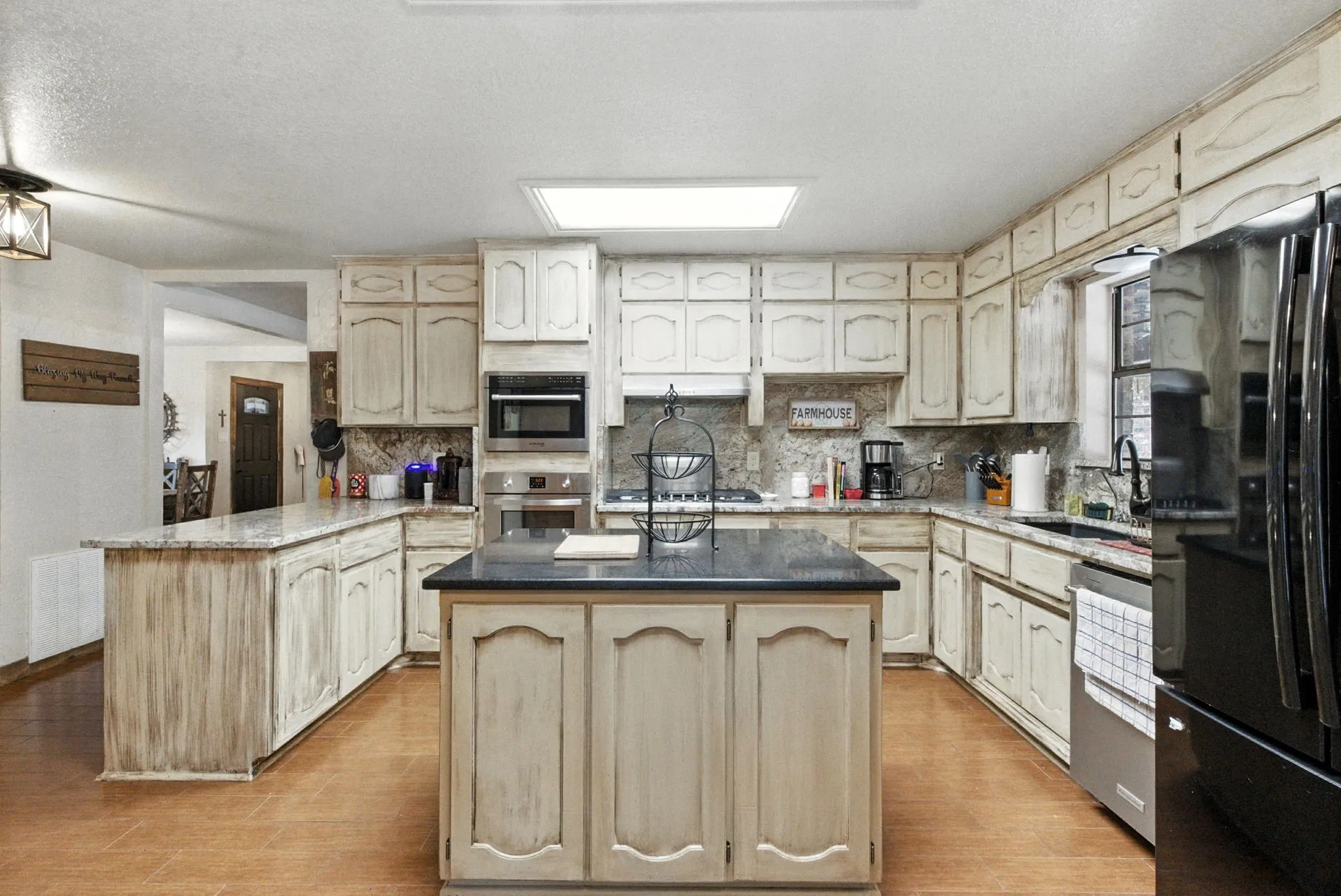 Kitchen with decorative backsplash, a kitchen island, stainless steel appliances, light wood-style floors, and a peninsula