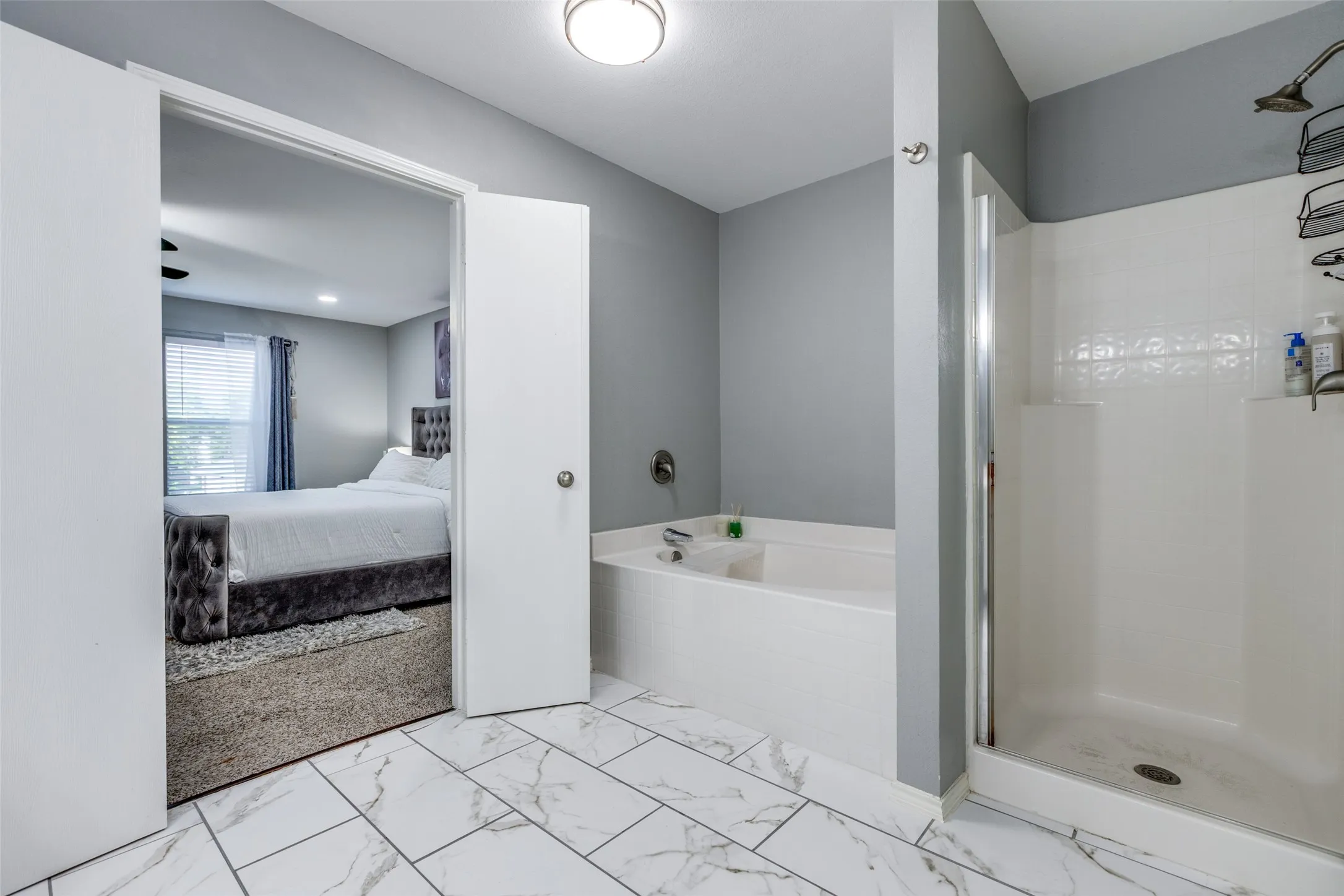 Ensuite bathroom with a bath, marble finish floors, and a stall shower