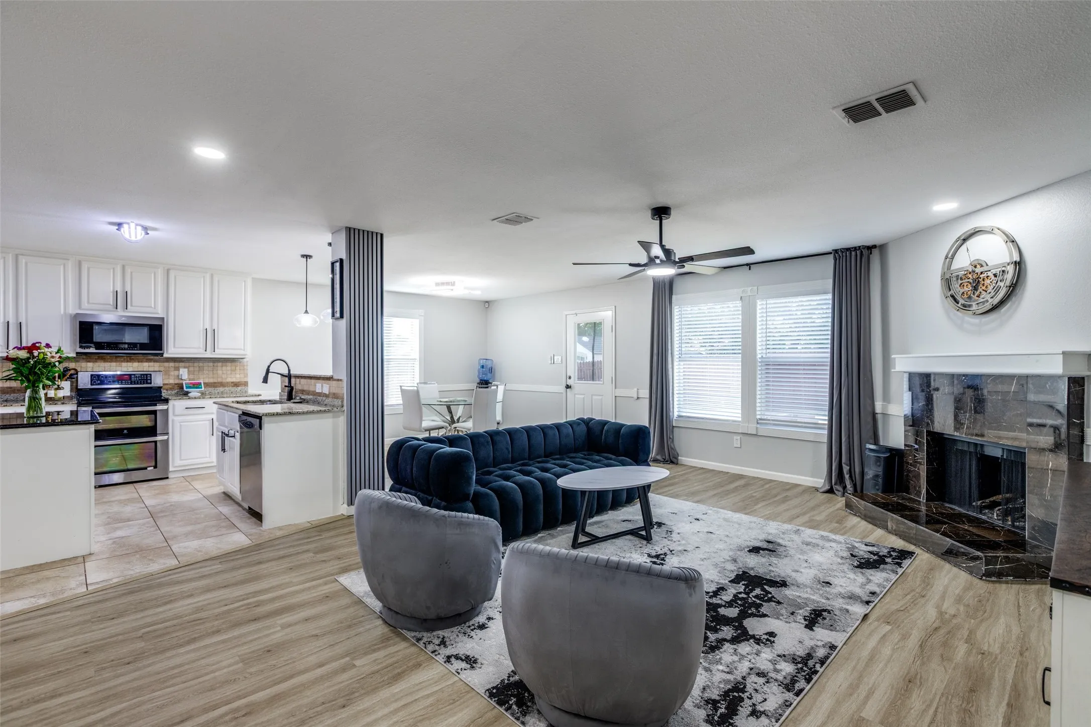 Living area featuring a fireplace, light wood-style floors, ceiling fan, and recessed lighting