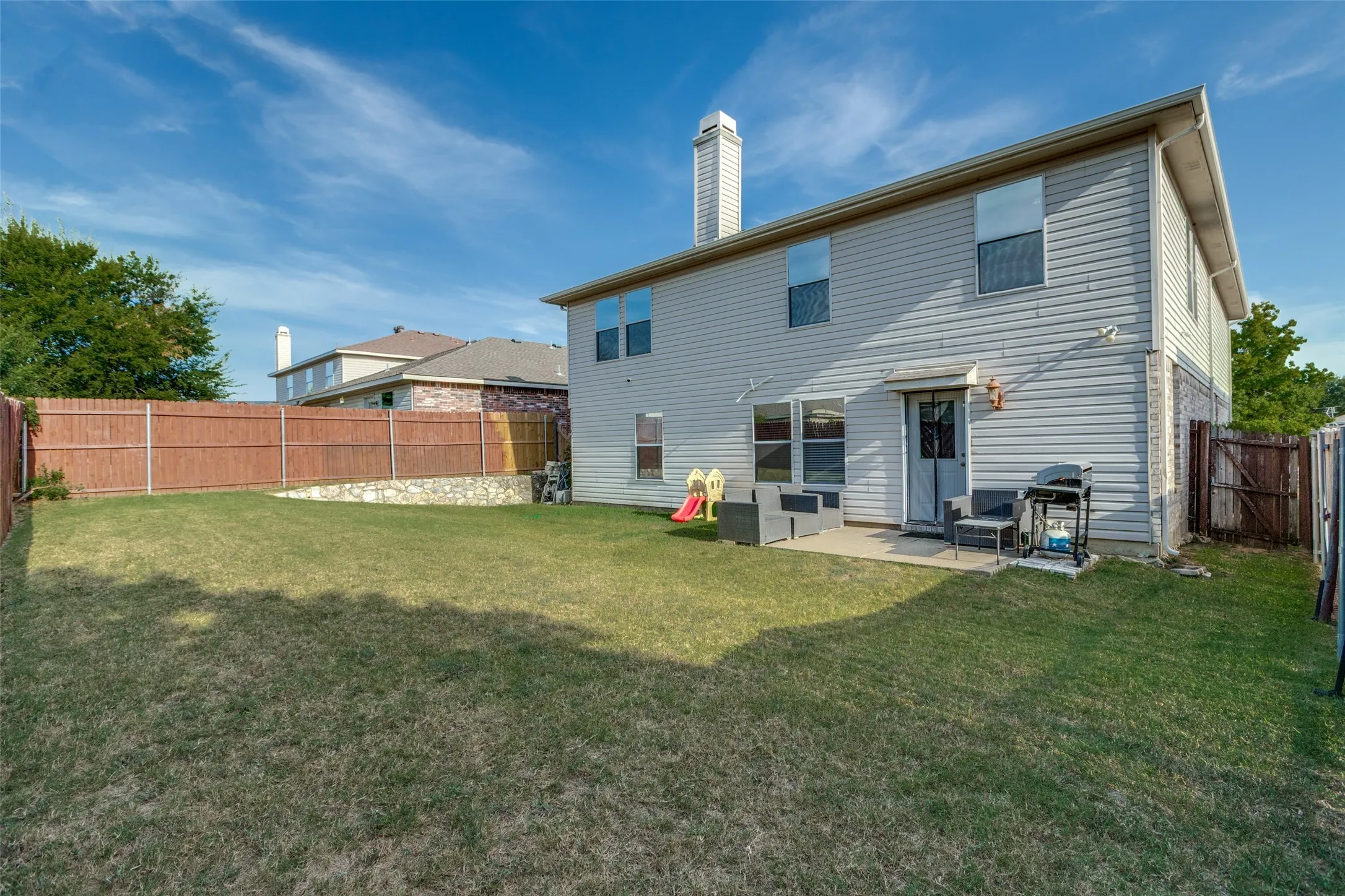 Back of property with a fenced backyard, a chimney, and a patio area