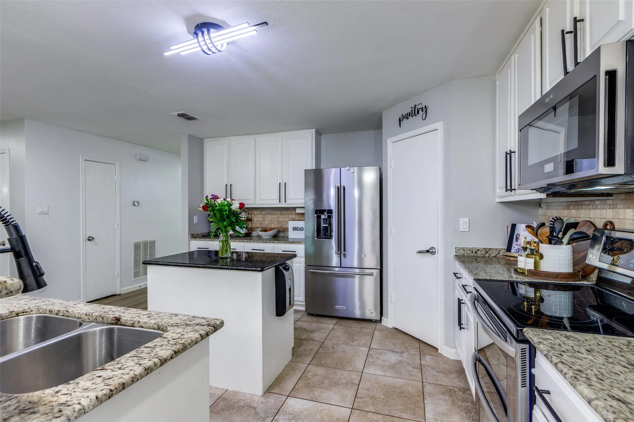 Kitchen with stainless steel appliances, a center island, backsplash, and white cabinets