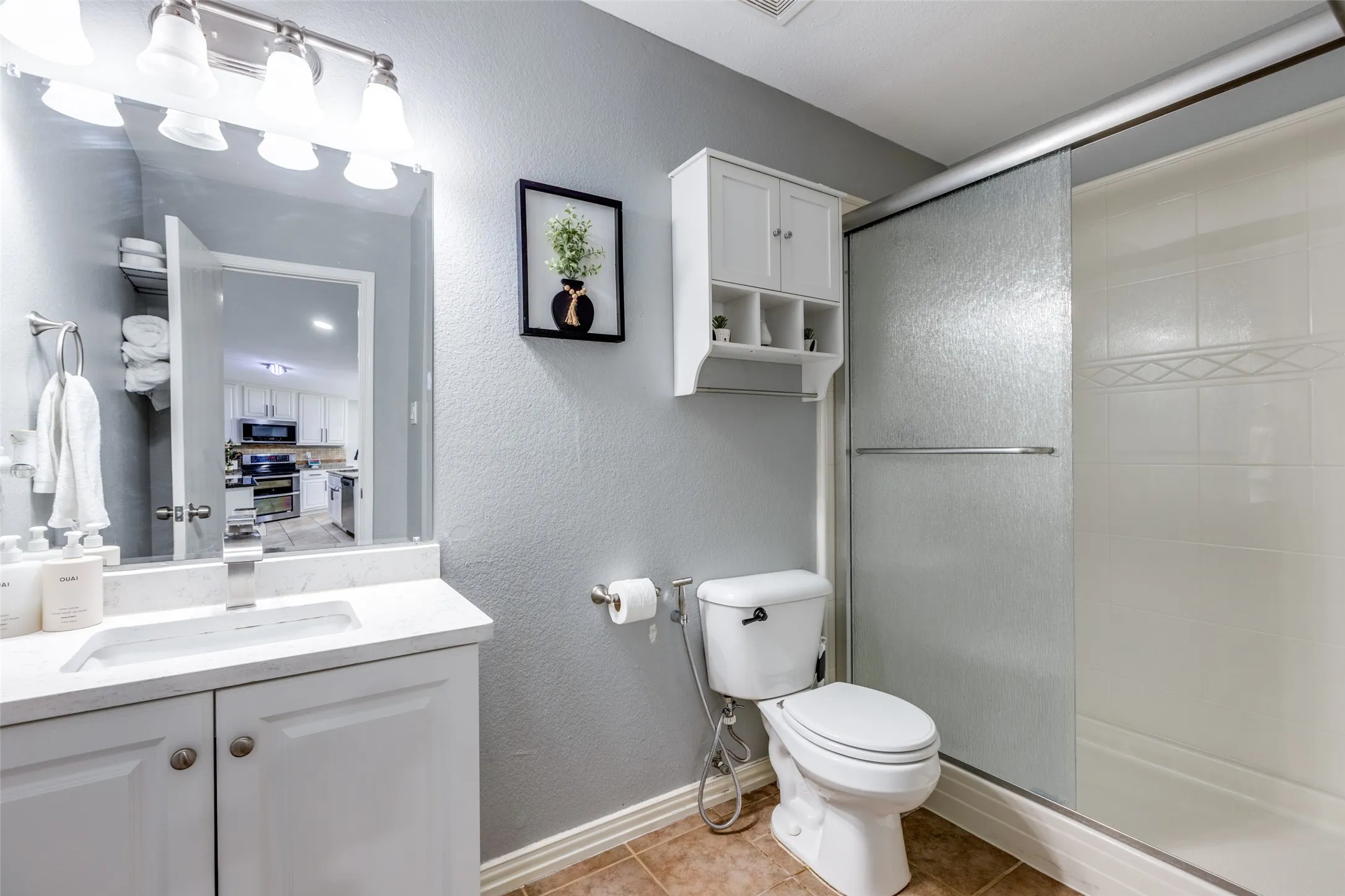 Bathroom with a stall shower, vanity, tile patterned flooring, and a textured wall