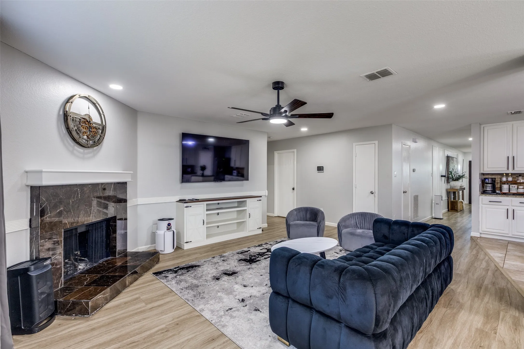 Living area with light wood-type flooring, a fireplace, recessed lighting, and ceiling fan