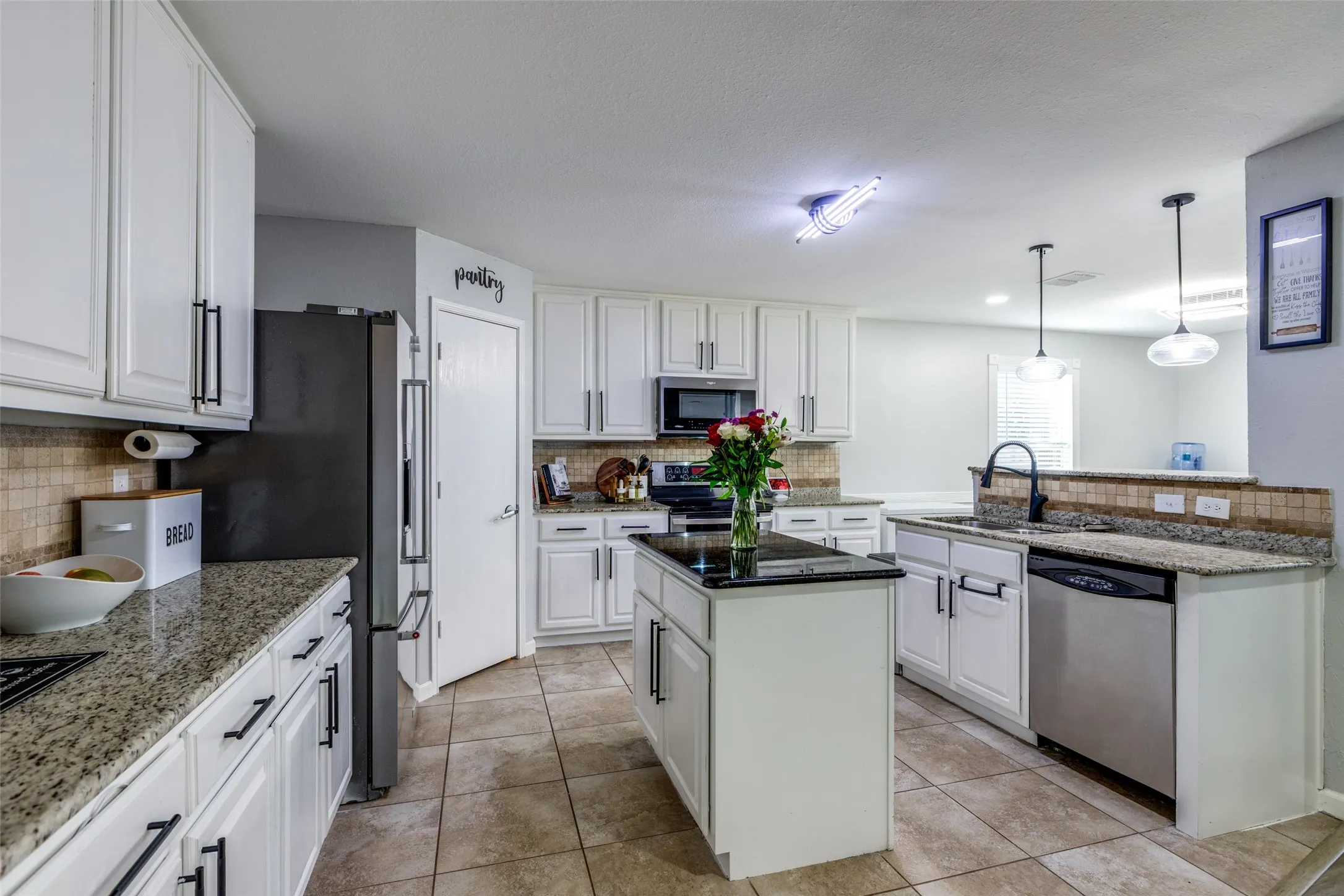 Kitchen with a kitchen island, tasteful backsplash, stainless steel appliances, white cabinets, and a textured ceiling