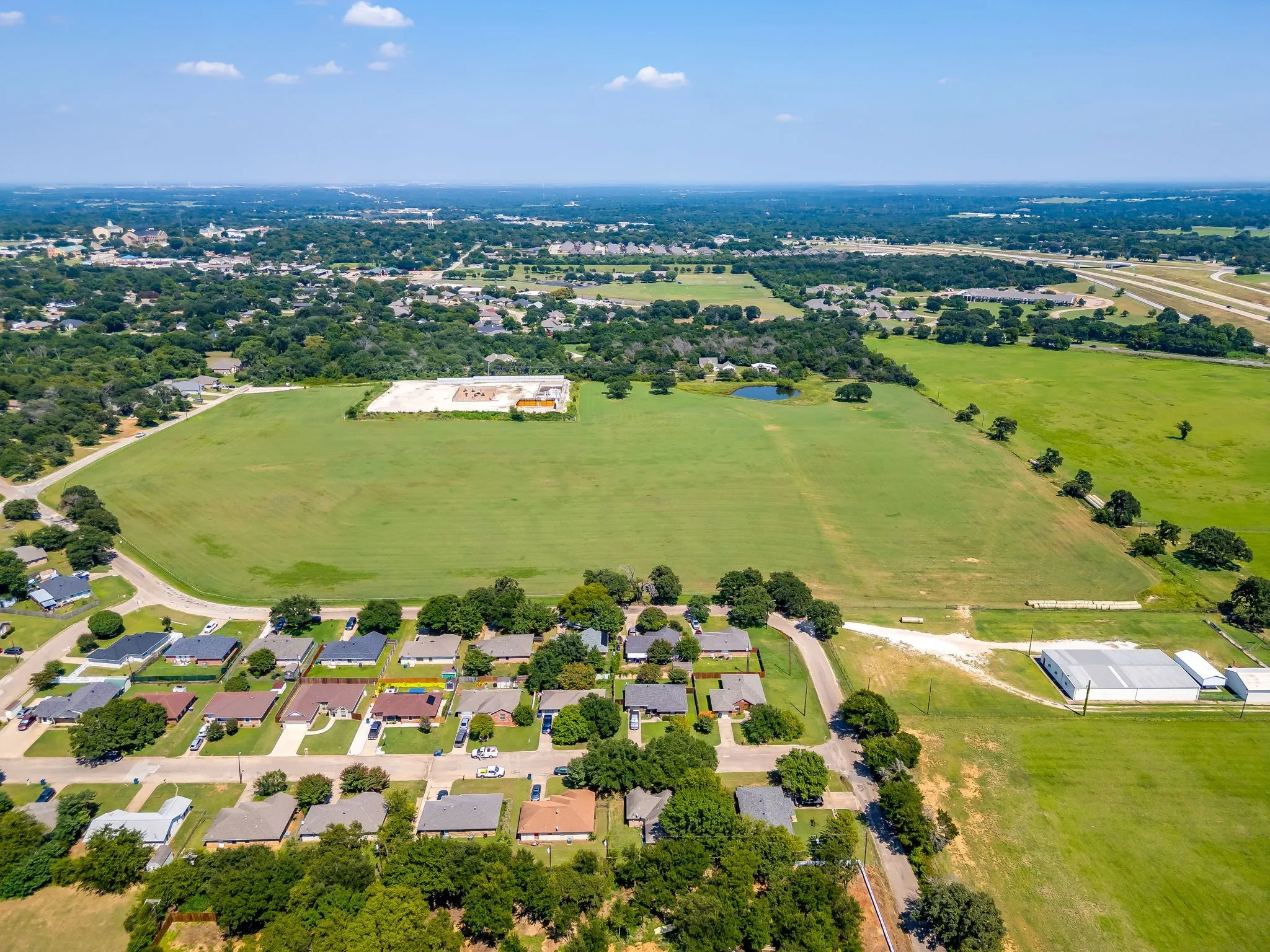 Aerial overview of property's location with nearby suburban area and a tree filled landscape