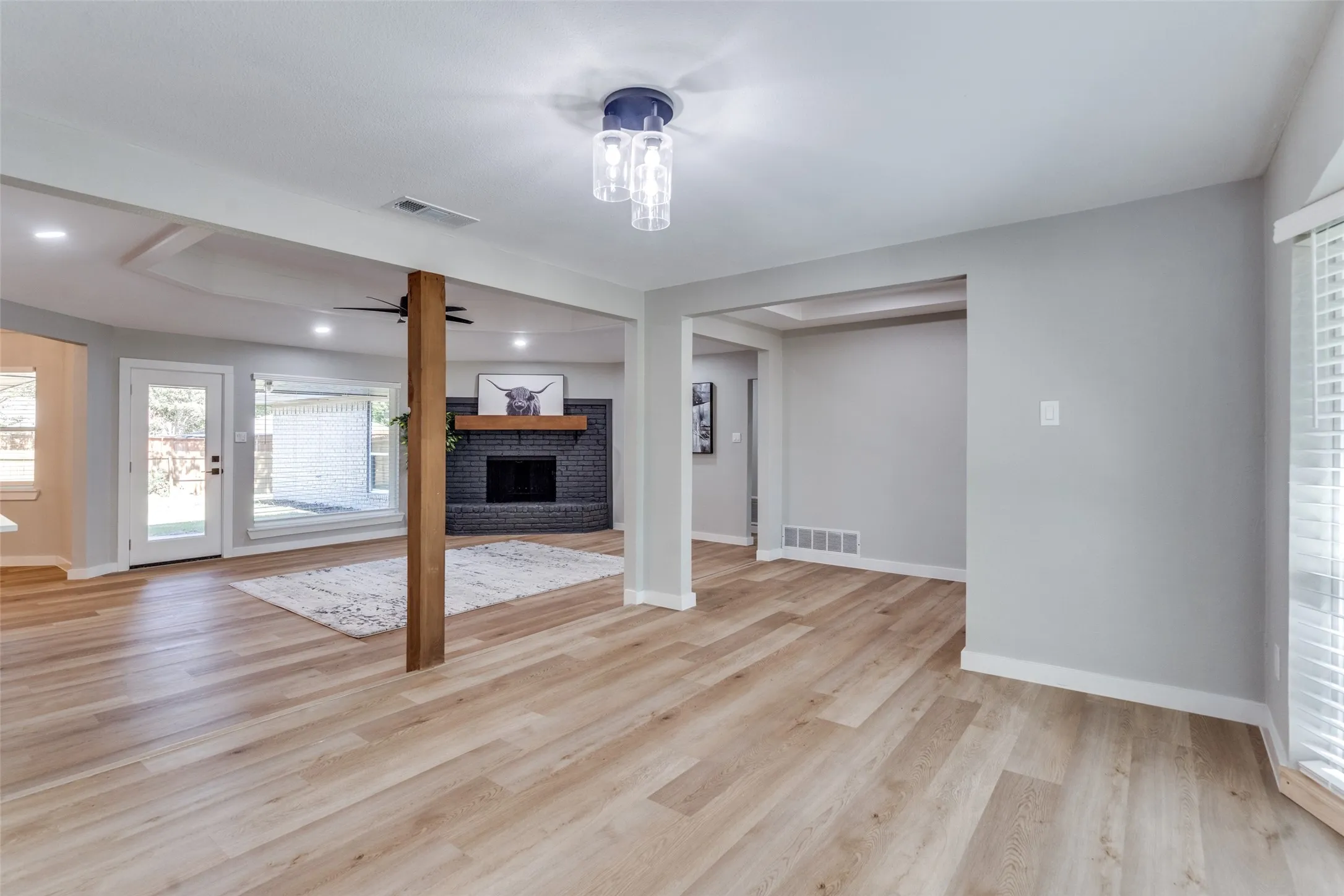 Unfurnished living room with healthy amount of natural light, a fireplace, light wood finished floors, and ceiling fan