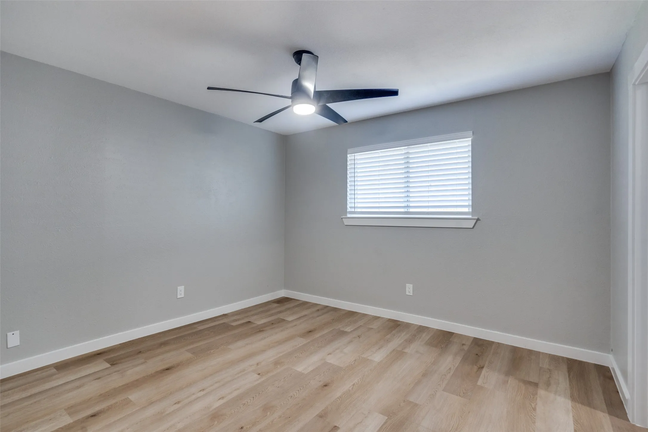 Empty room with light wood-type flooring and a ceiling fan