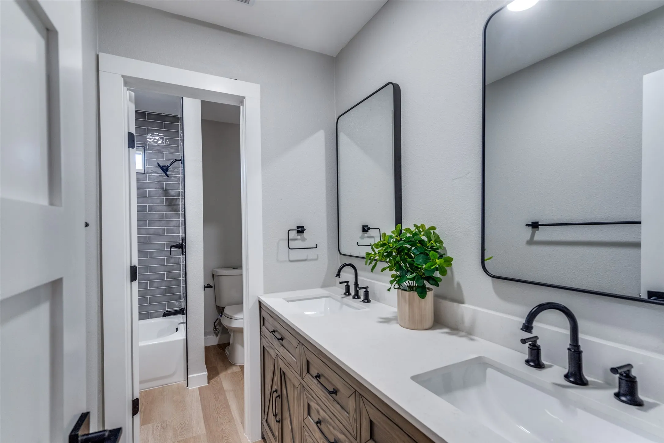Bathroom with wood finished floors, double vanity, and shower / bath combination