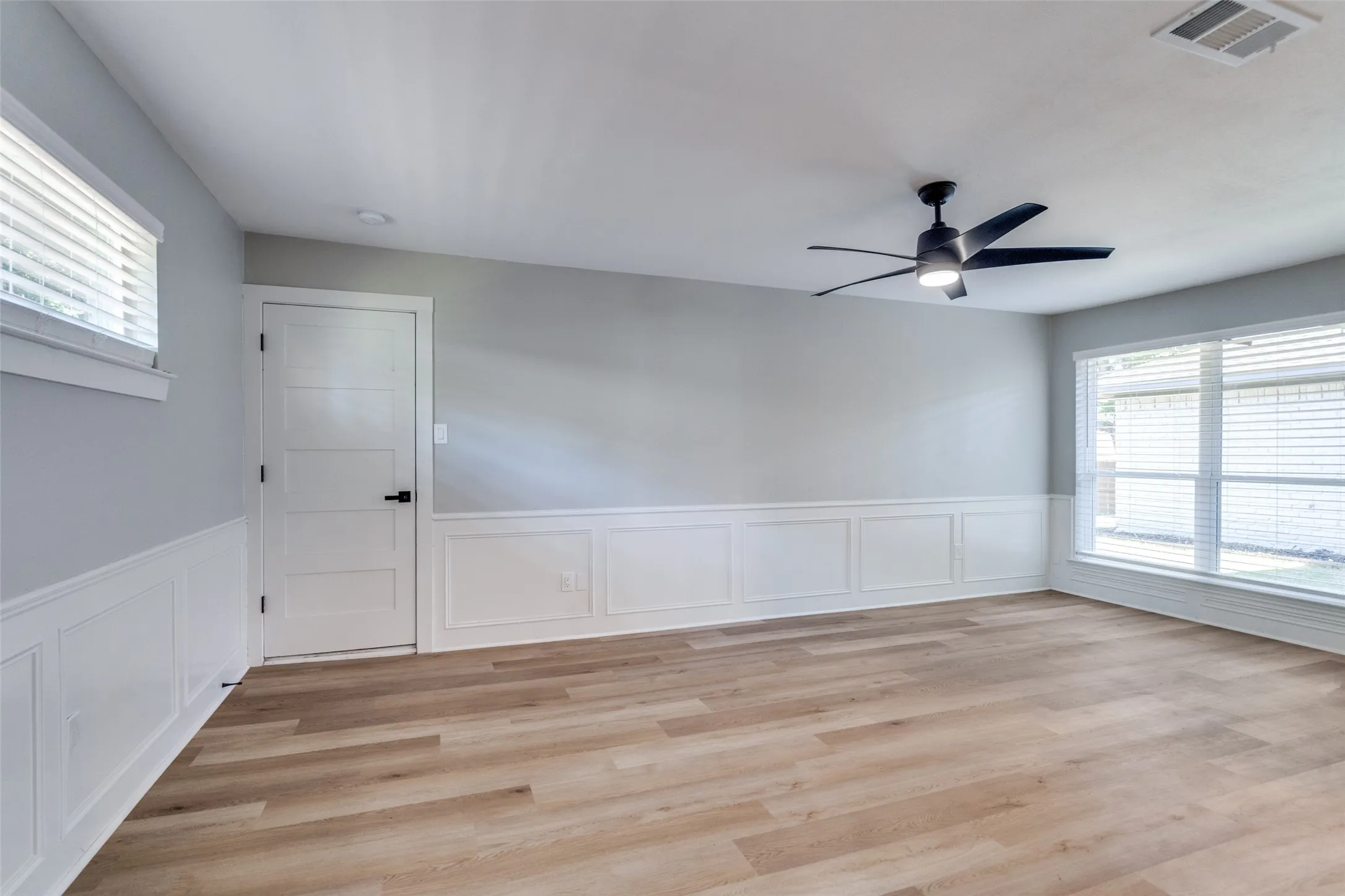 Unfurnished room with wainscoting, a ceiling fan, light wood-style floors, and a decorative wall