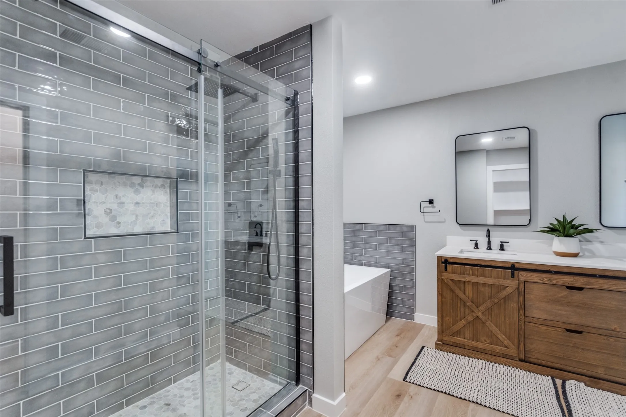 Bathroom with a freestanding bath, a shower stall, vanity, wood finished floors, and recessed lighting