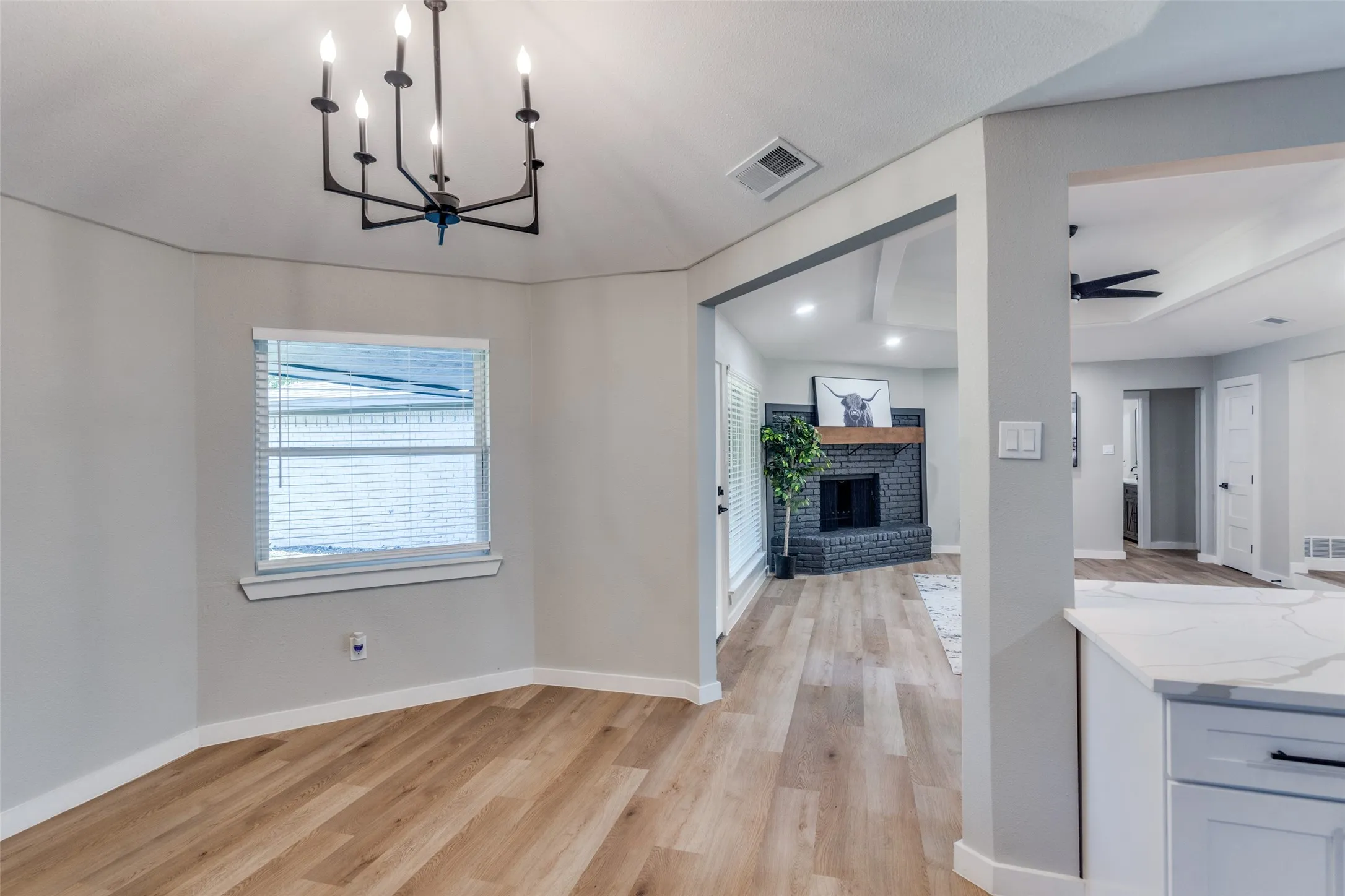 Unfurnished dining area featuring light wood finished floors, healthy amount of natural light, a brick fireplace, a ceiling fan, and recessed lighting
