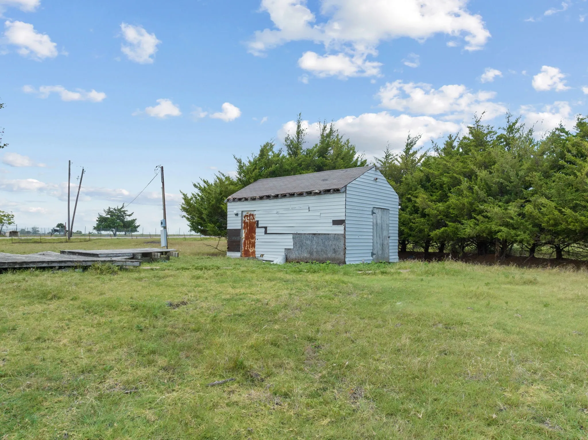 View of green lawn with an outdoor structure and a rural view