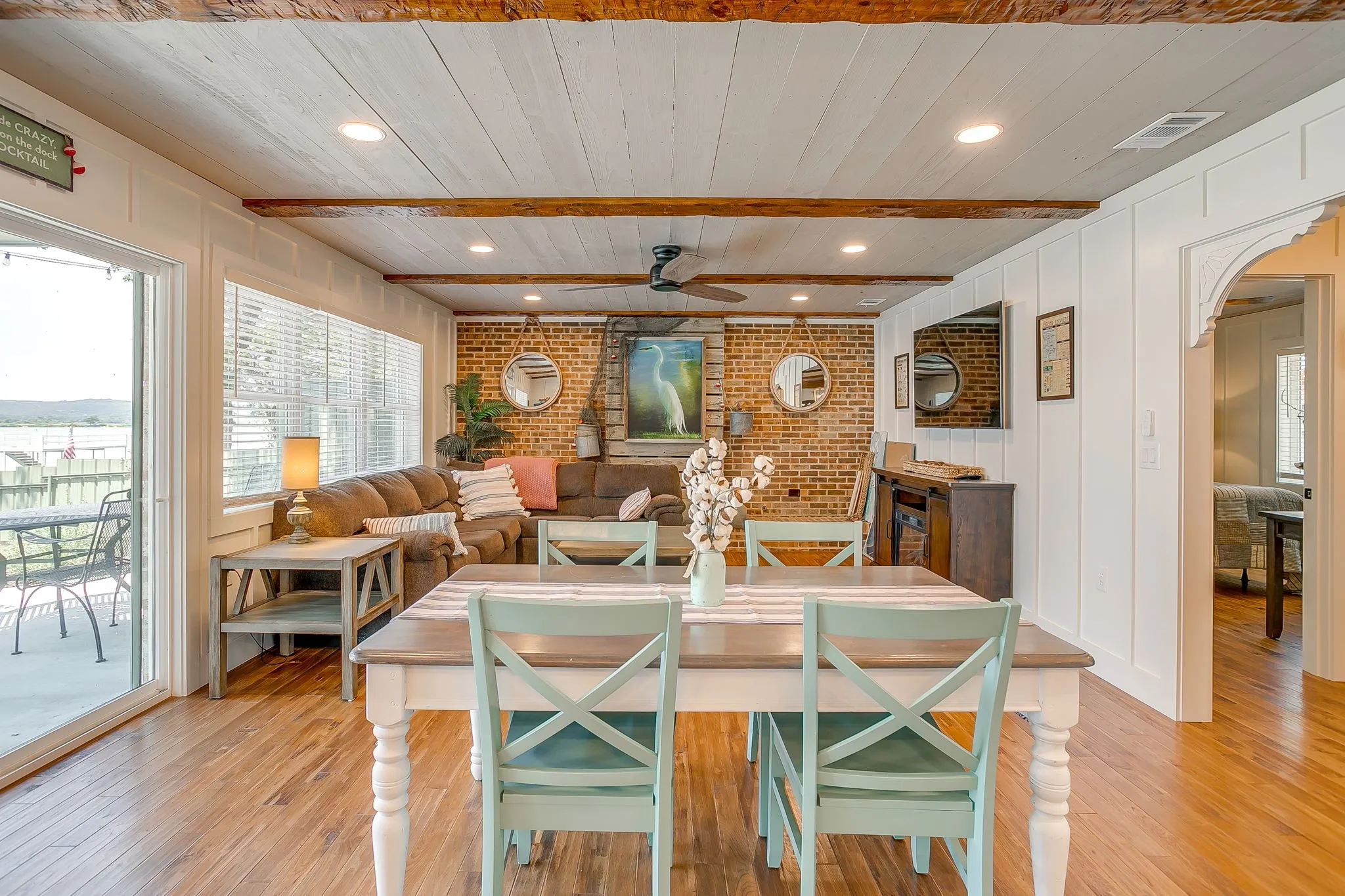 Dining room featuring recessed lighting, light wood-style floors, brick wall, a wooden ceiling with exposed beams, and arched walkways