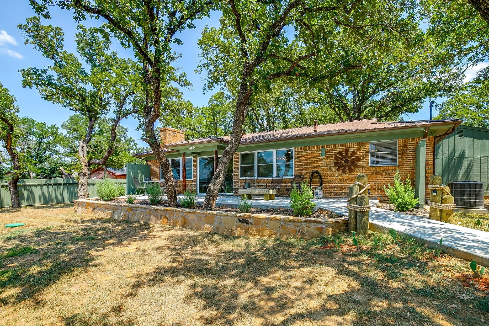 Ranch-style house with brick siding, a chimney, a metal roof, and a patio area
