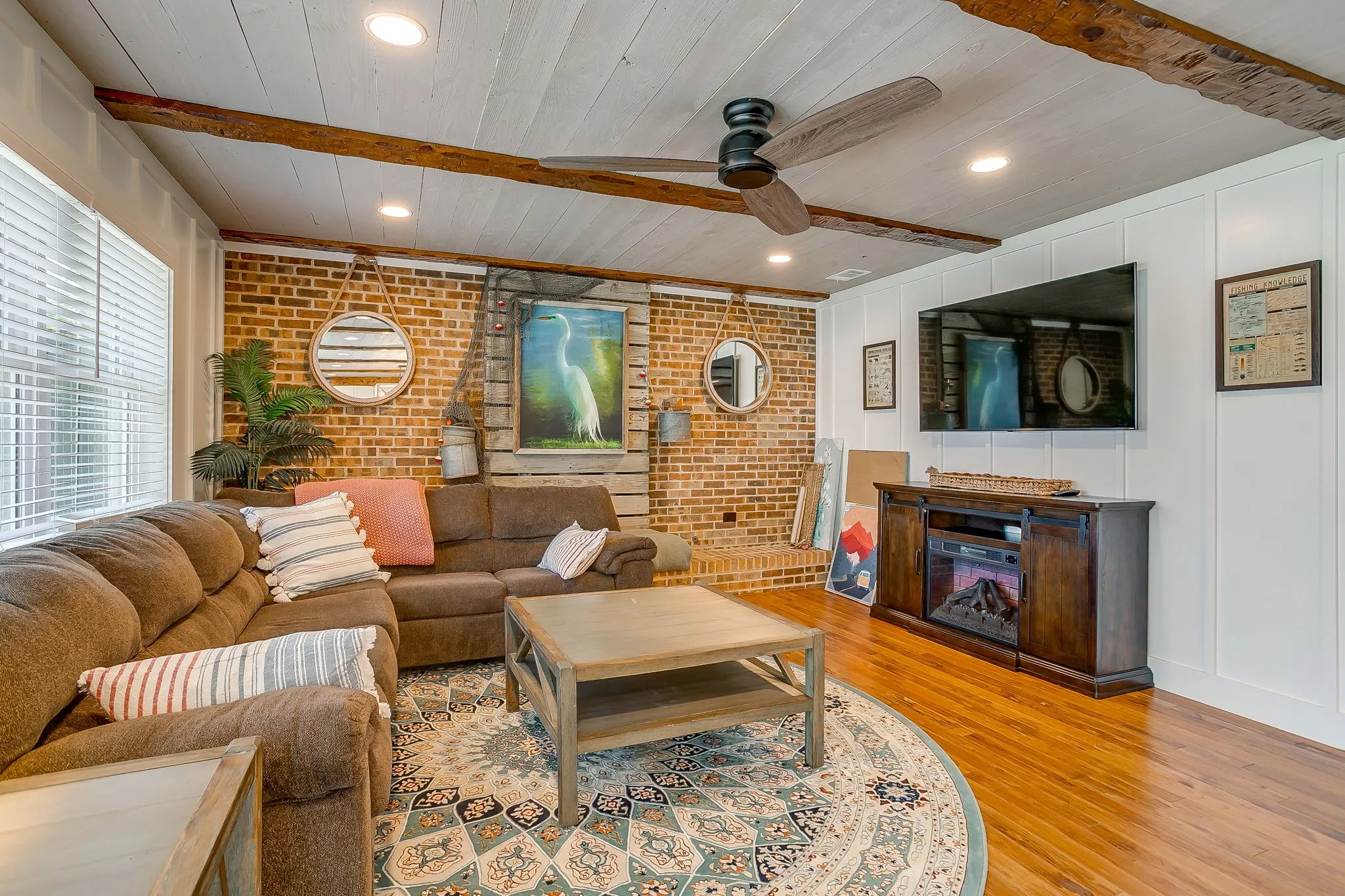 Living room featuring brick wall, light wood-style flooring, recessed lighting, a wood ceiling with exposed beams, and a ceiling fan