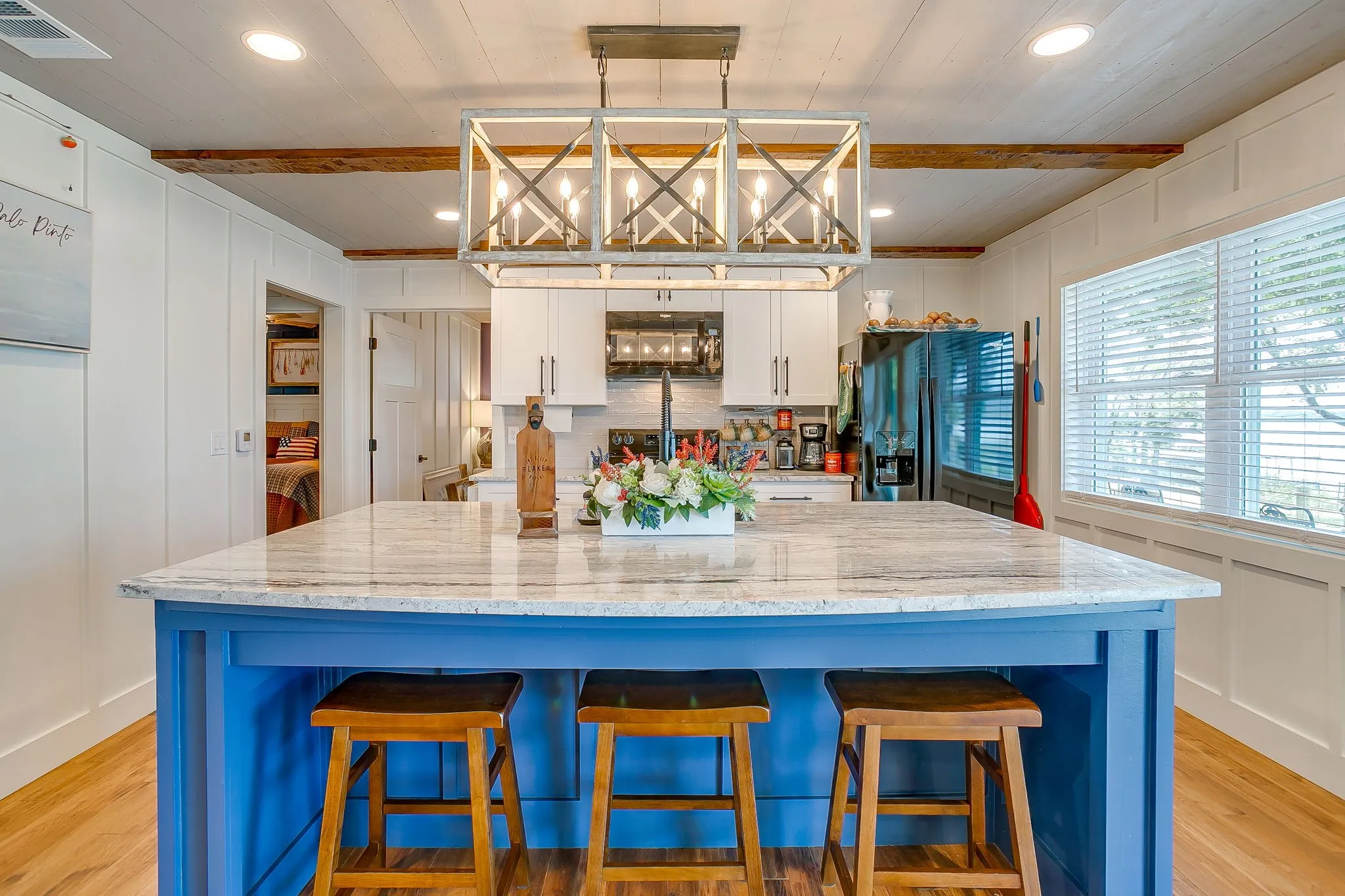 Kitchen with a decorative wall, light wood-type flooring, white cabinets, black appliances, and recessed lighting
