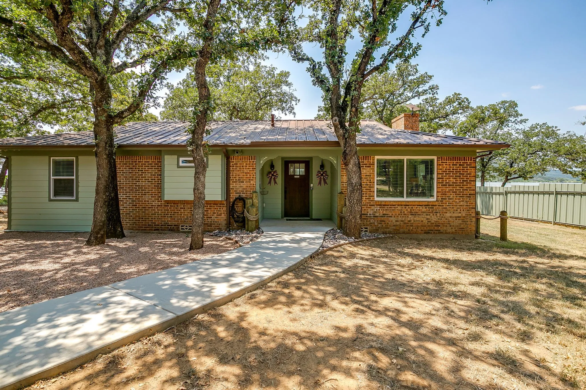 Ranch-style house featuring brick siding, a metal roof, and a chimney
