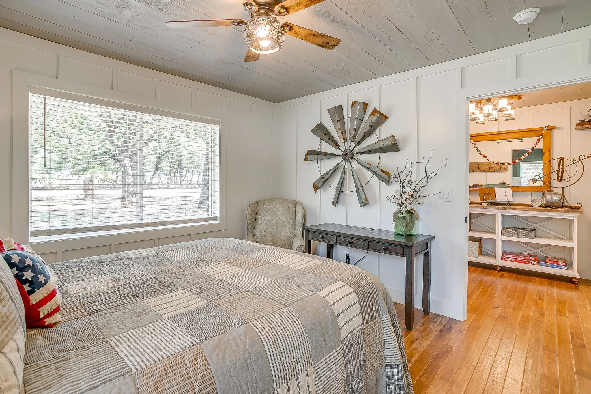Bedroom with light wood-type flooring, a decorative wall, wooden ceiling, a chandelier, and a ceiling fan