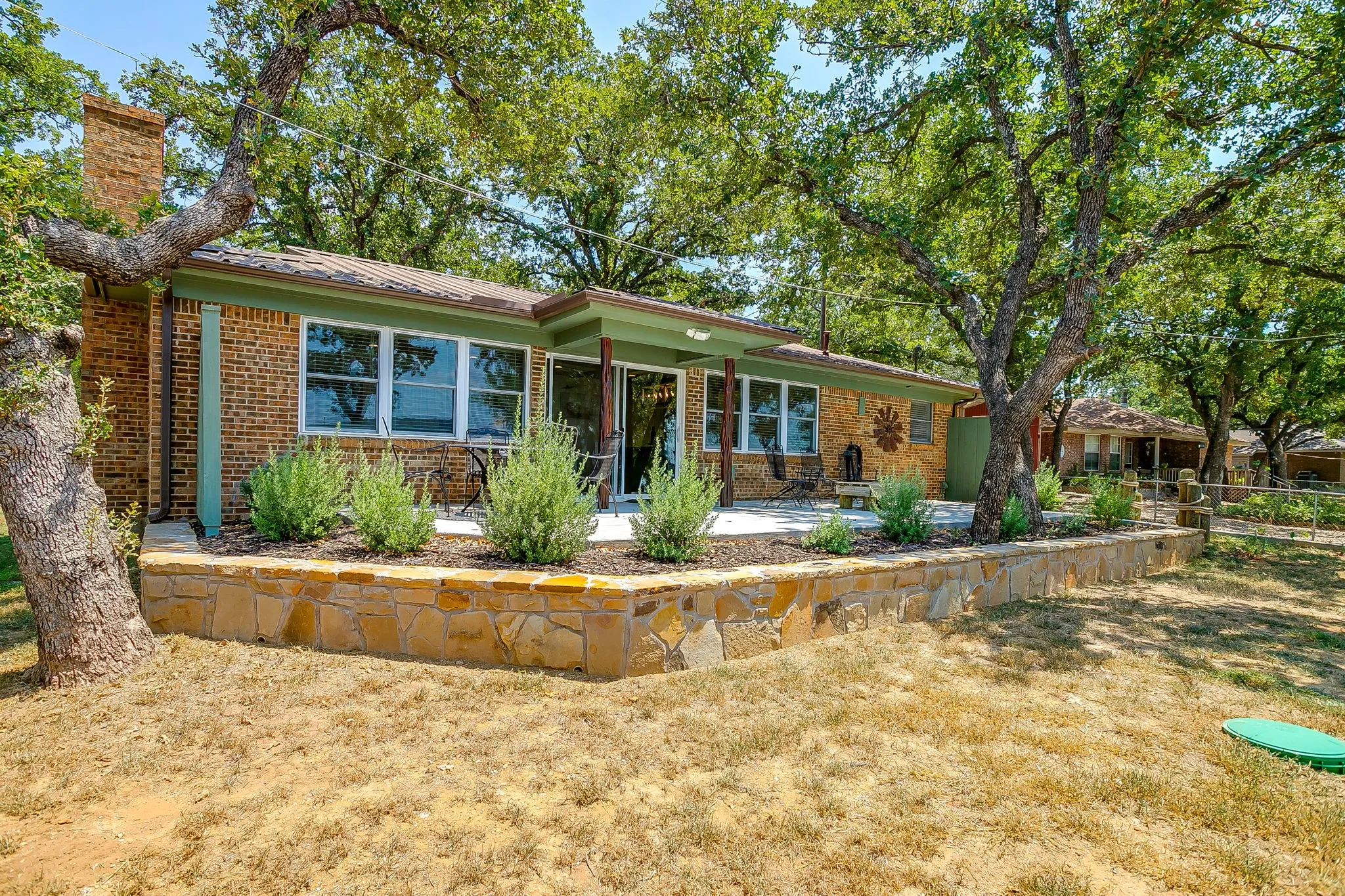 Ranch-style home featuring brick siding, a metal roof, and a chimney