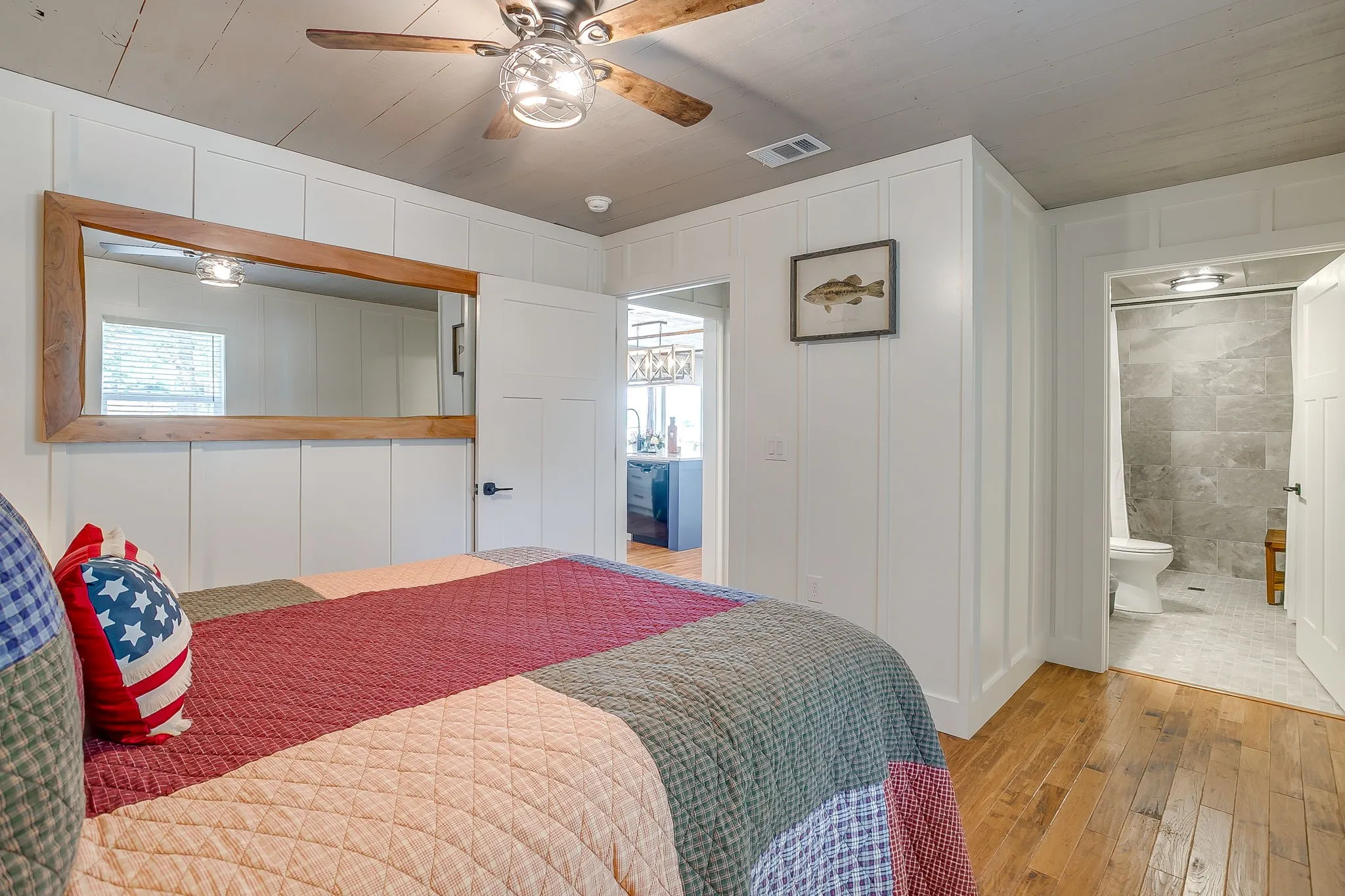 Bedroom with a decorative wall, light wood-style floors, and a ceiling fan
