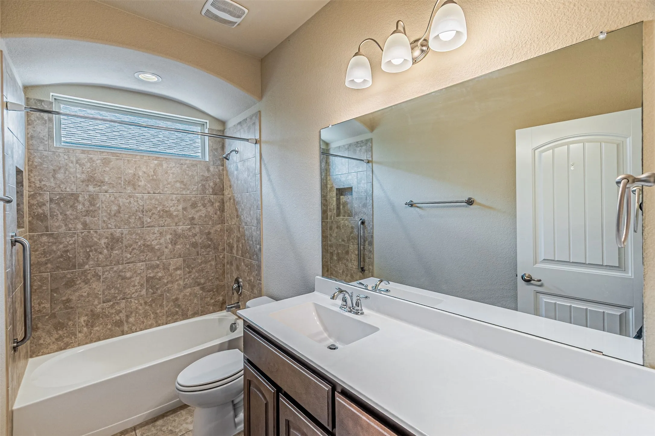 Bathroom featuring a textured wall, washtub / shower combination, vanity, and tile patterned floors
