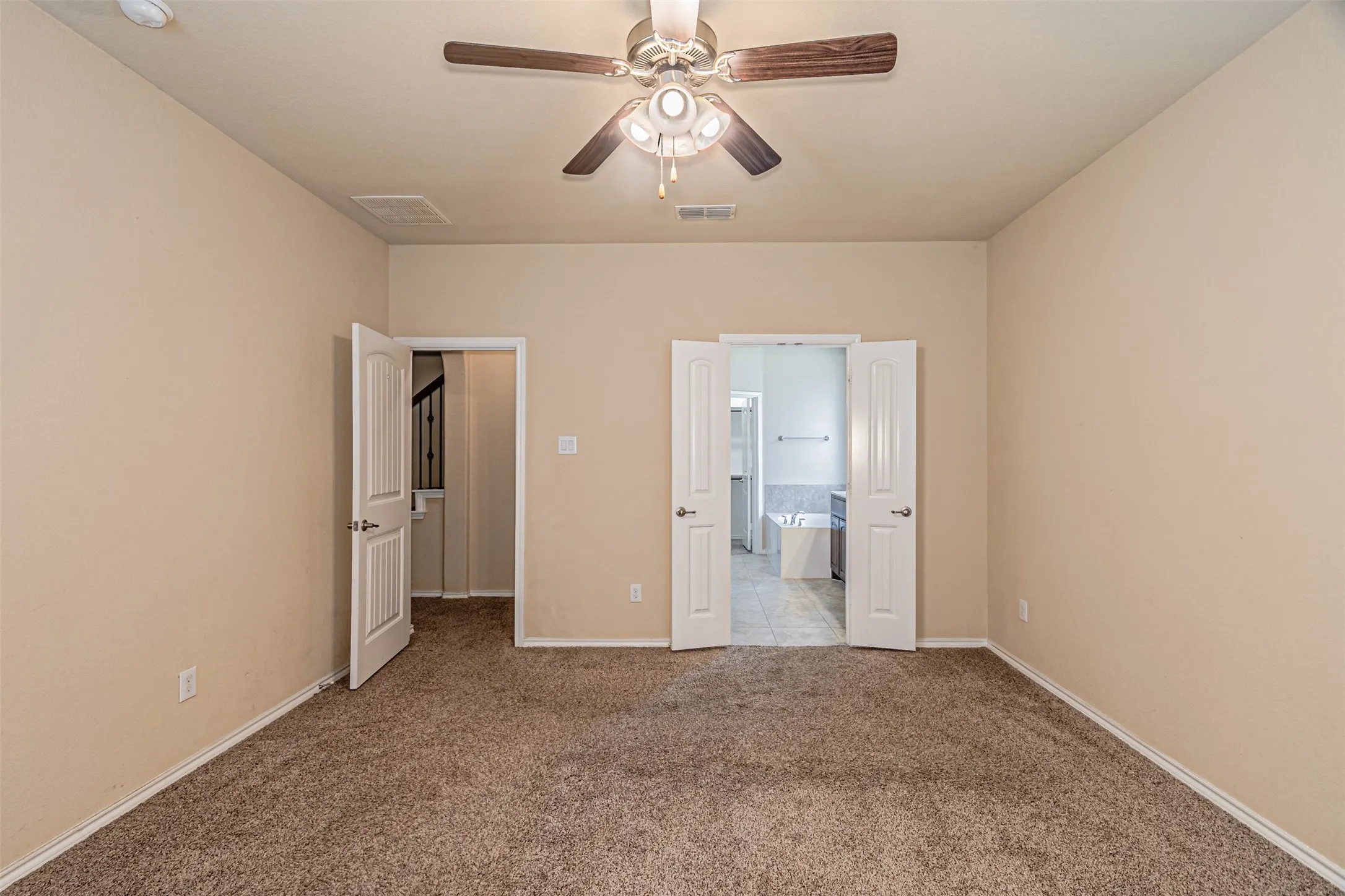 Unfurnished bedroom featuring carpet, connected bathroom, and a ceiling fan