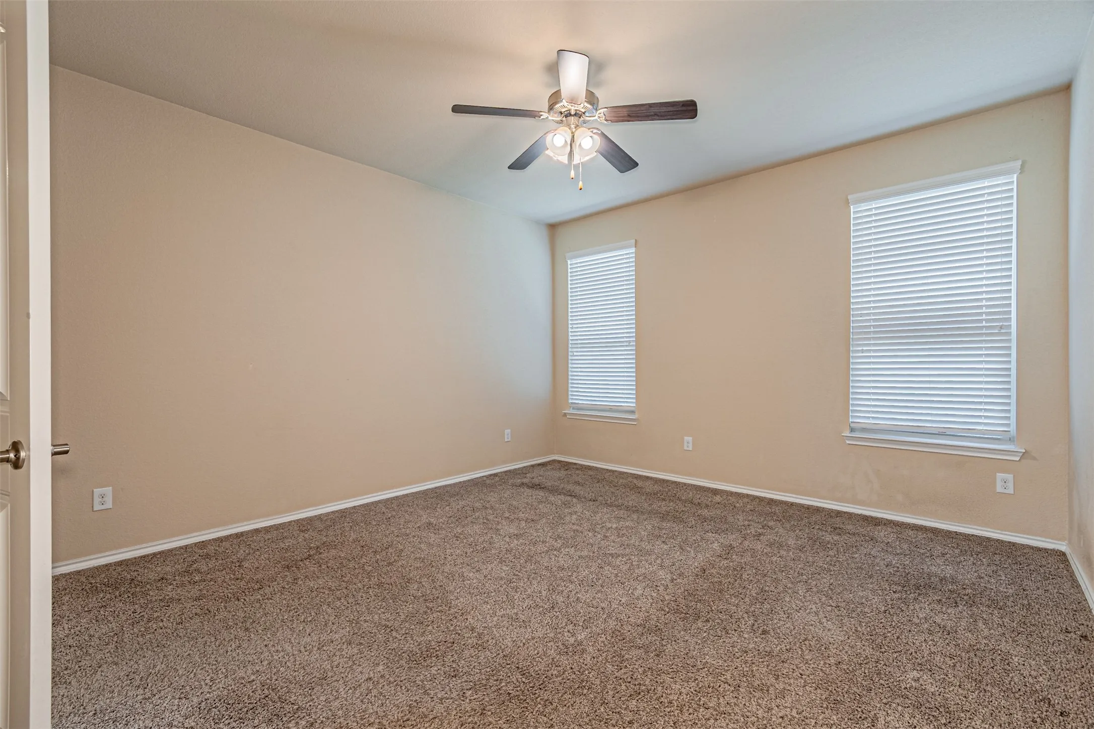 Carpeted spare room featuring baseboards and a ceiling fan