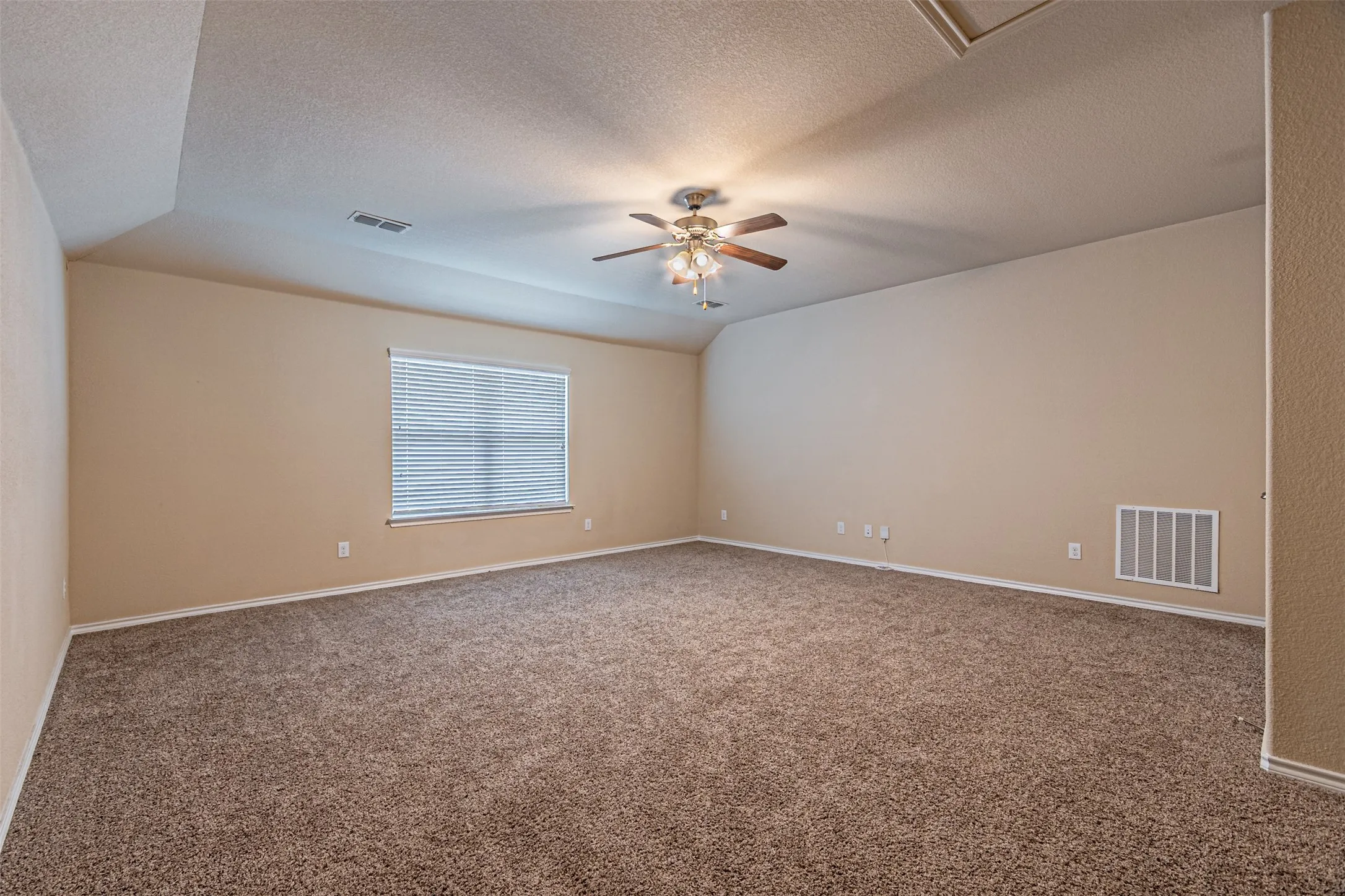 Unfurnished room with carpet floors, vaulted ceiling, a textured ceiling, and ceiling fan