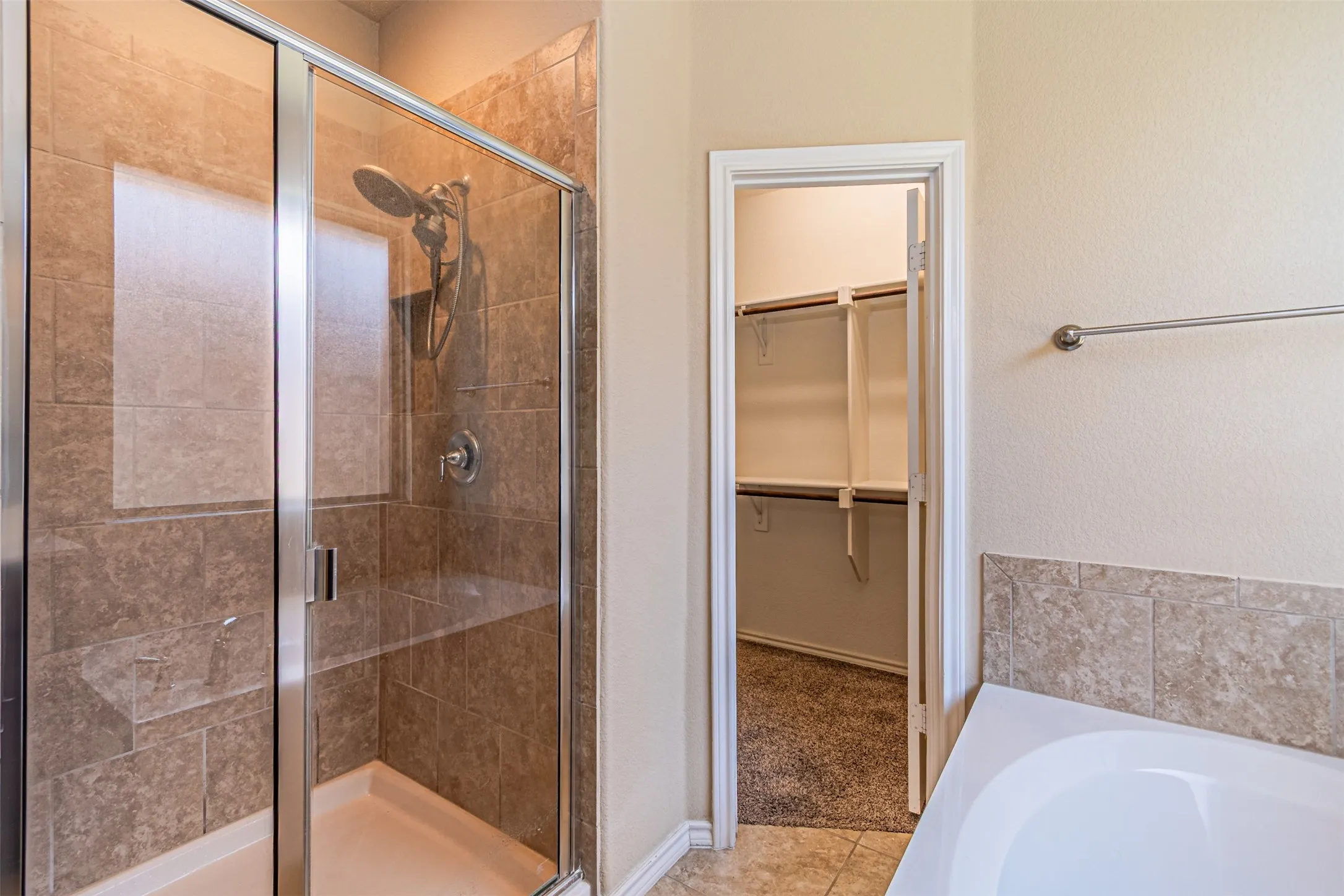 Full bath with a shower stall, a walk in closet, tile patterned flooring, and a bath