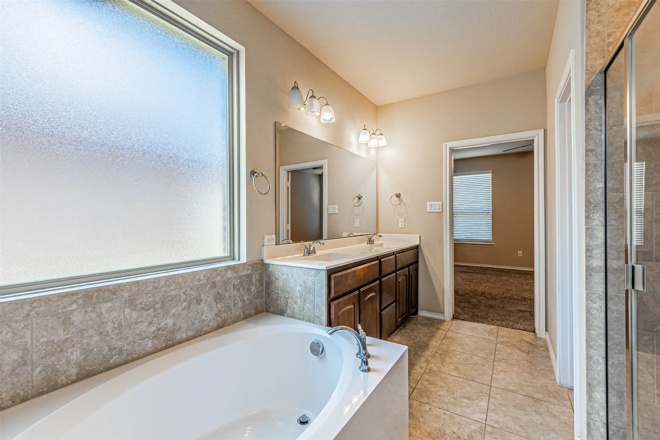 Full bathroom with tile patterned flooring, a garden tub, double vanity, and tiled shower