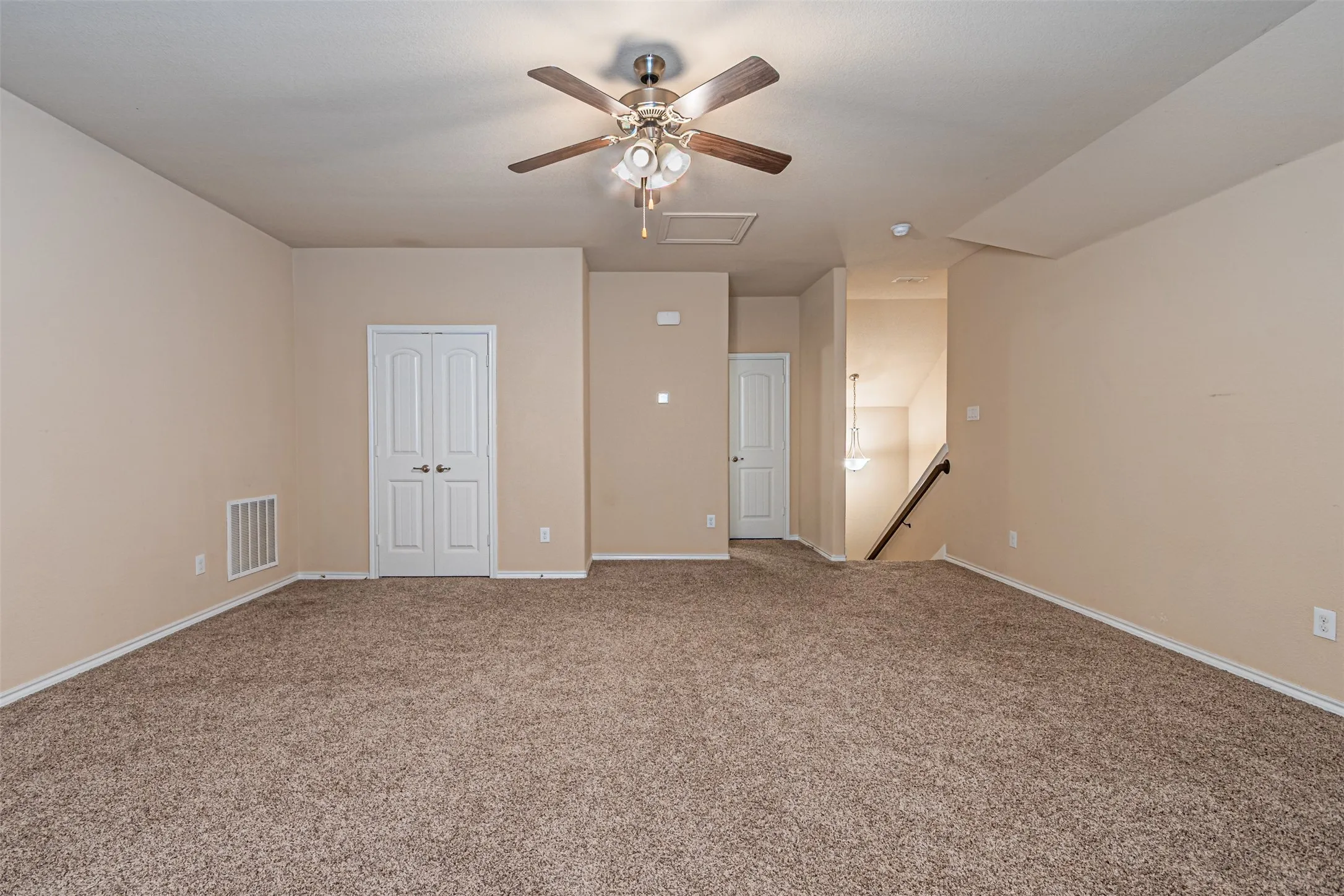 Carpeted spare room with attic access and ceiling fan
