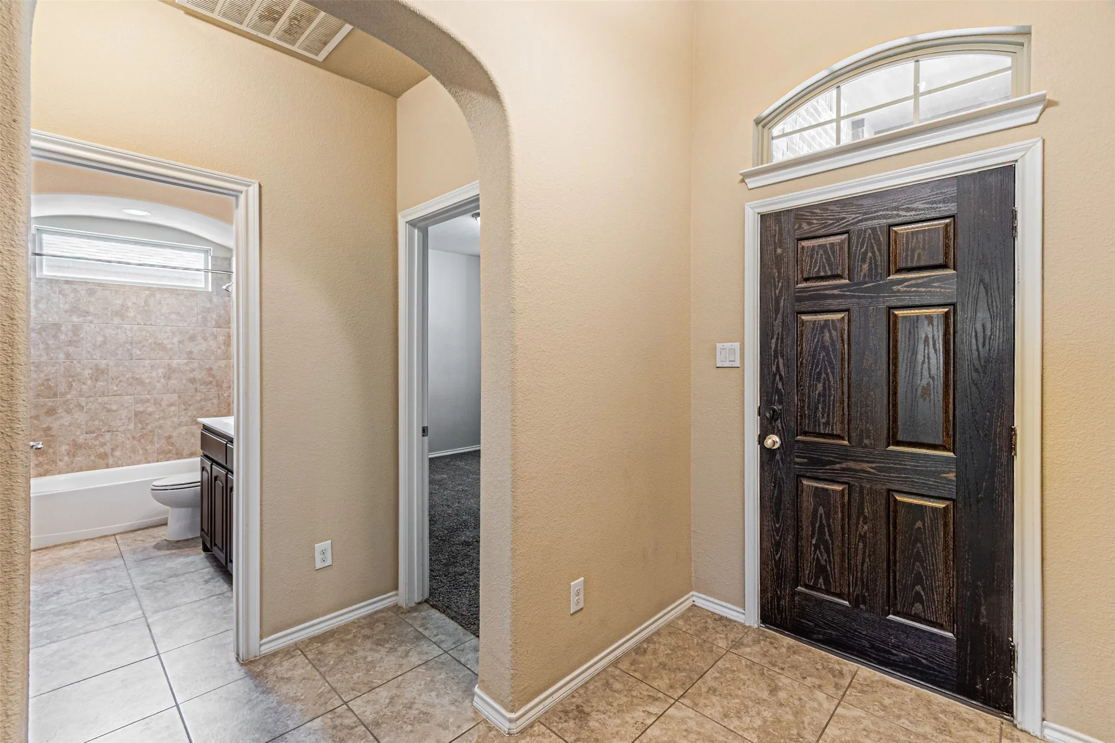 Foyer featuring healthy amount of natural light, arched walkways, and light tile patterned flooring