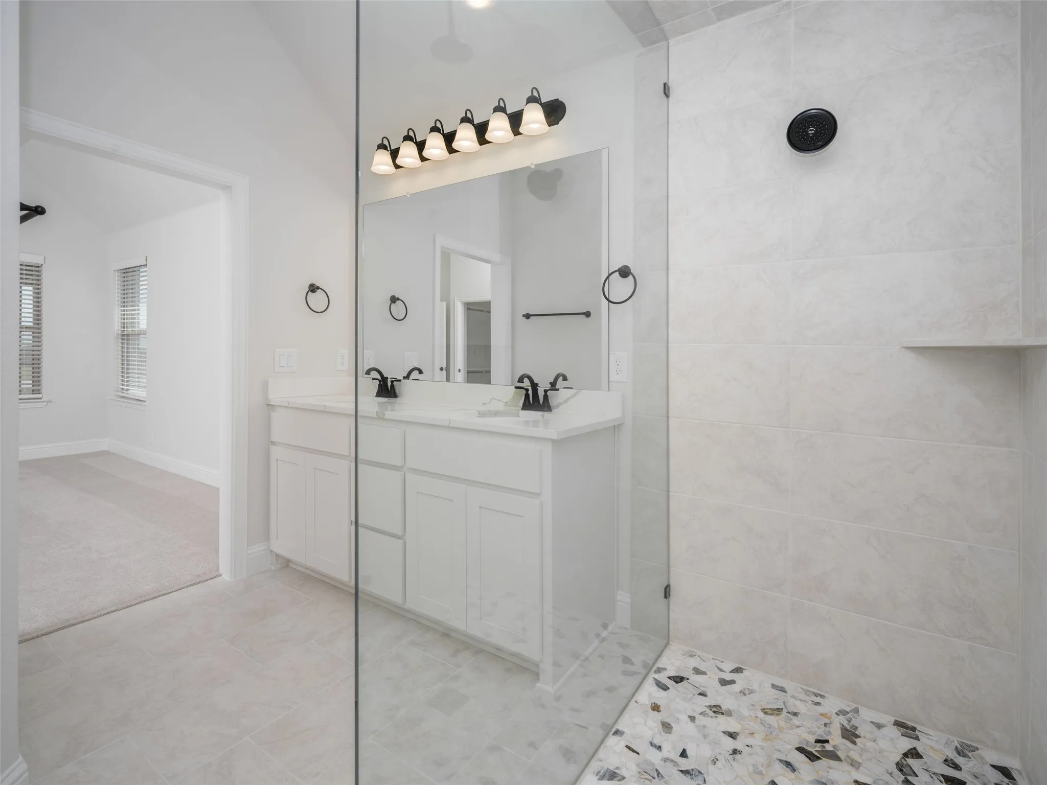 Full bathroom featuring double vanity, walk in shower, and light tile patterned flooring