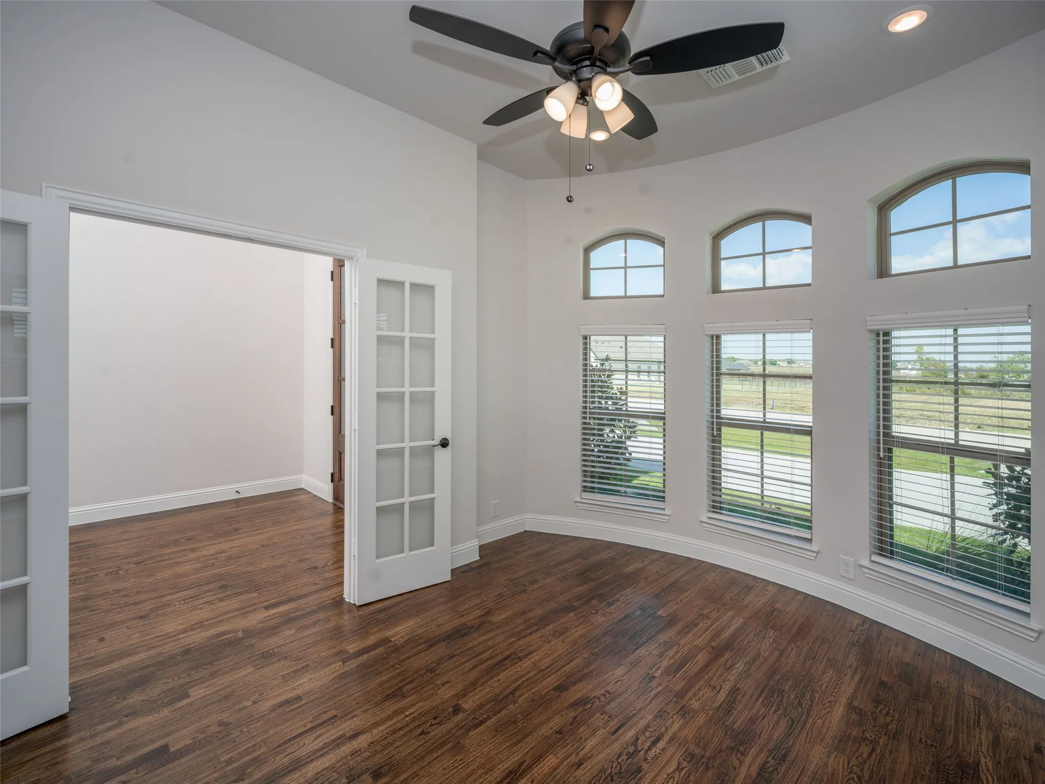 Empty room with dark wood-type flooring, ceiling fan, and recessed lighting