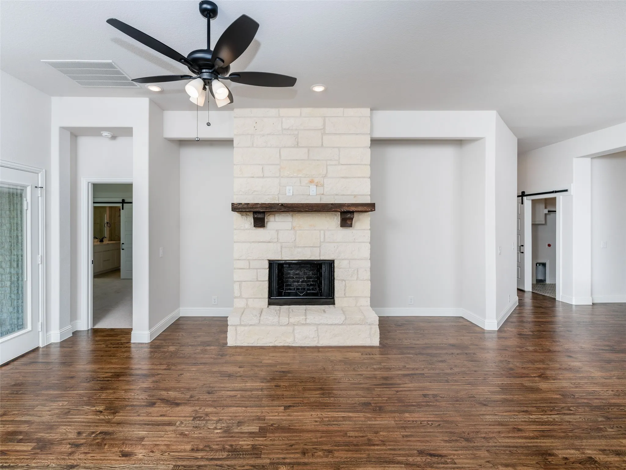 Unfurnished living room featuring a barn door, a fireplace, dark wood finished floors, ceiling fan, and recessed lighting