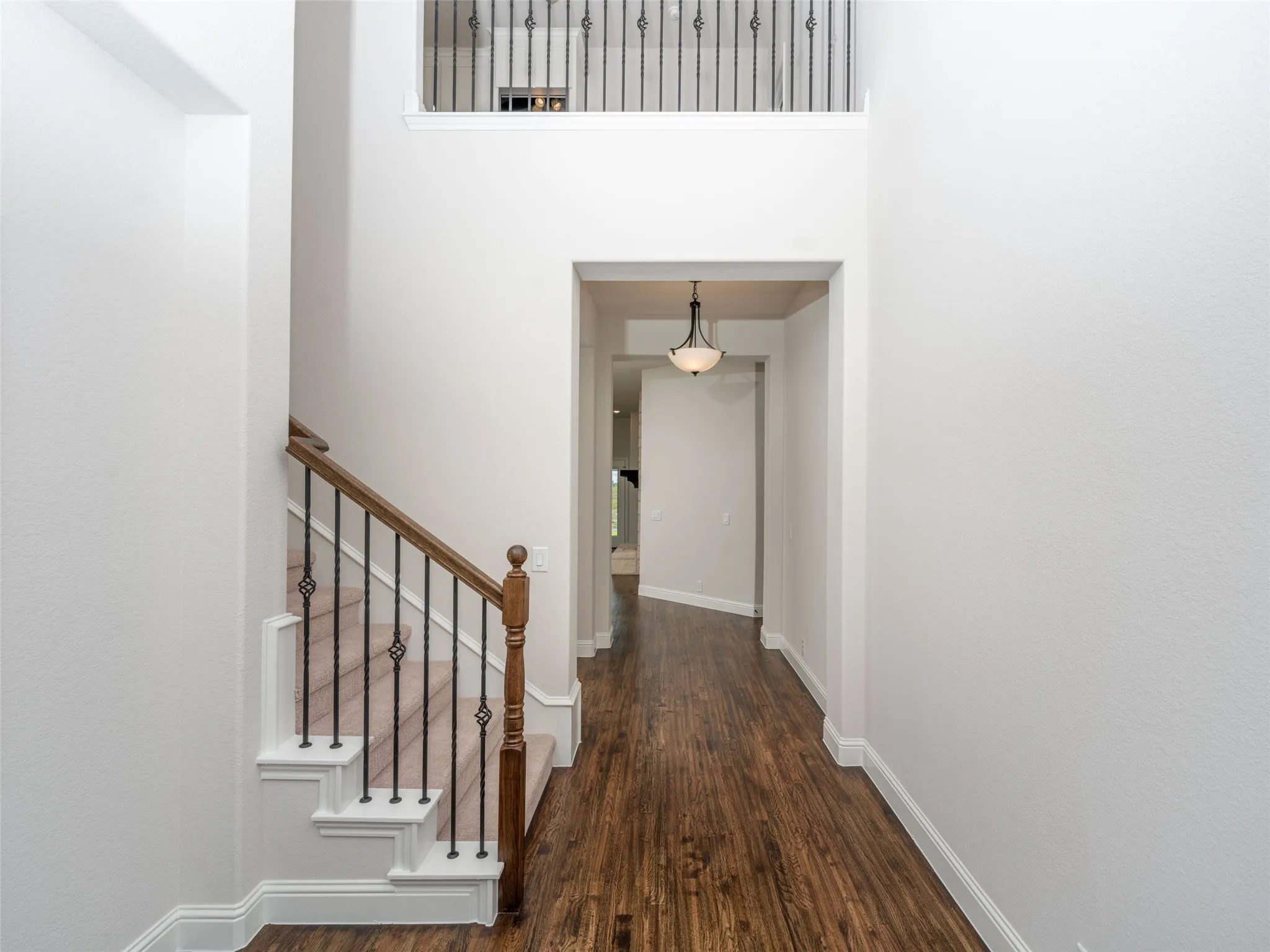 Hallway featuring dark wood-style floors, a towering ceiling, and stairs
