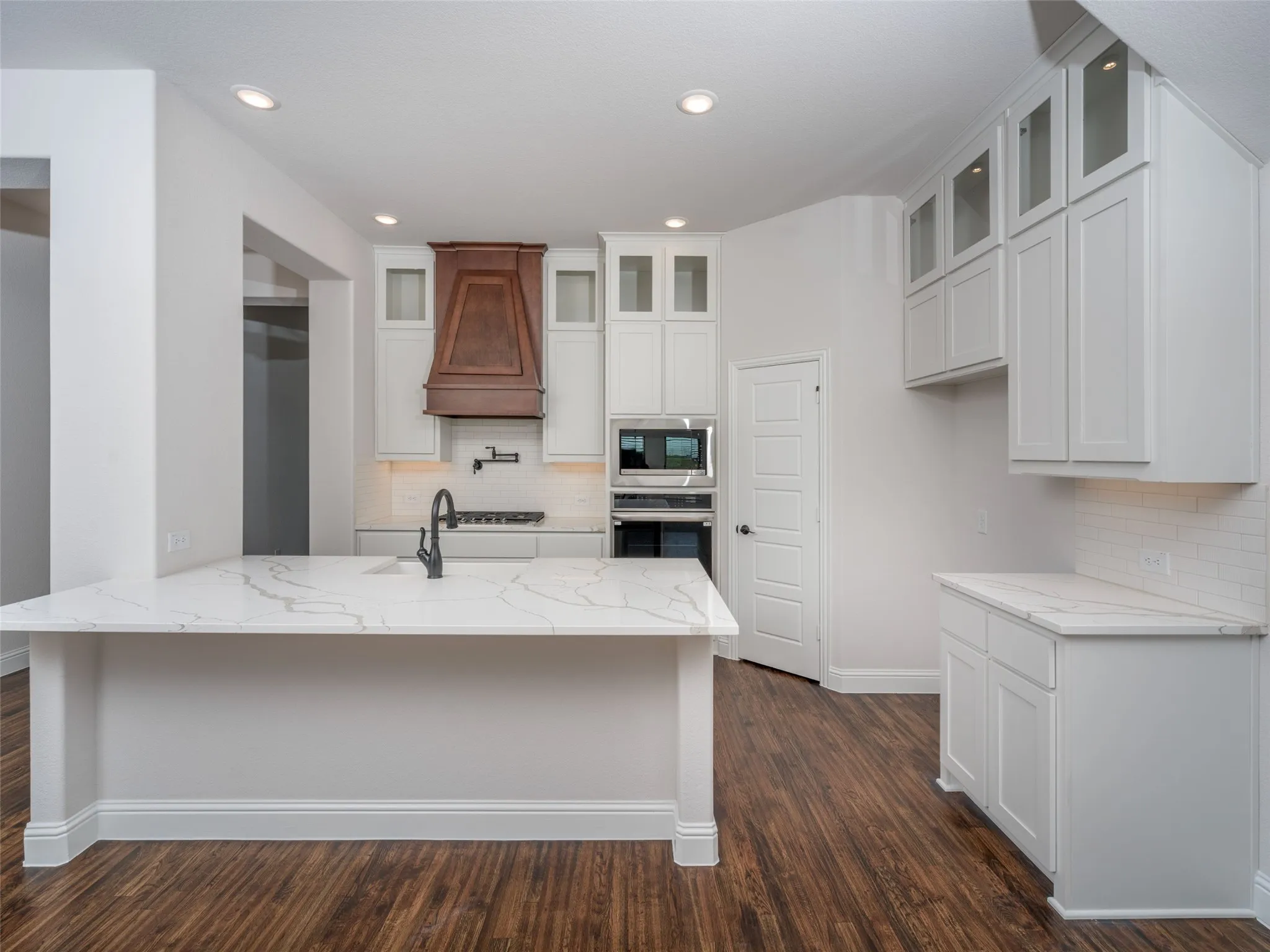 Kitchen with decorative backsplash, white cabinets, light stone counters, and recessed lighting