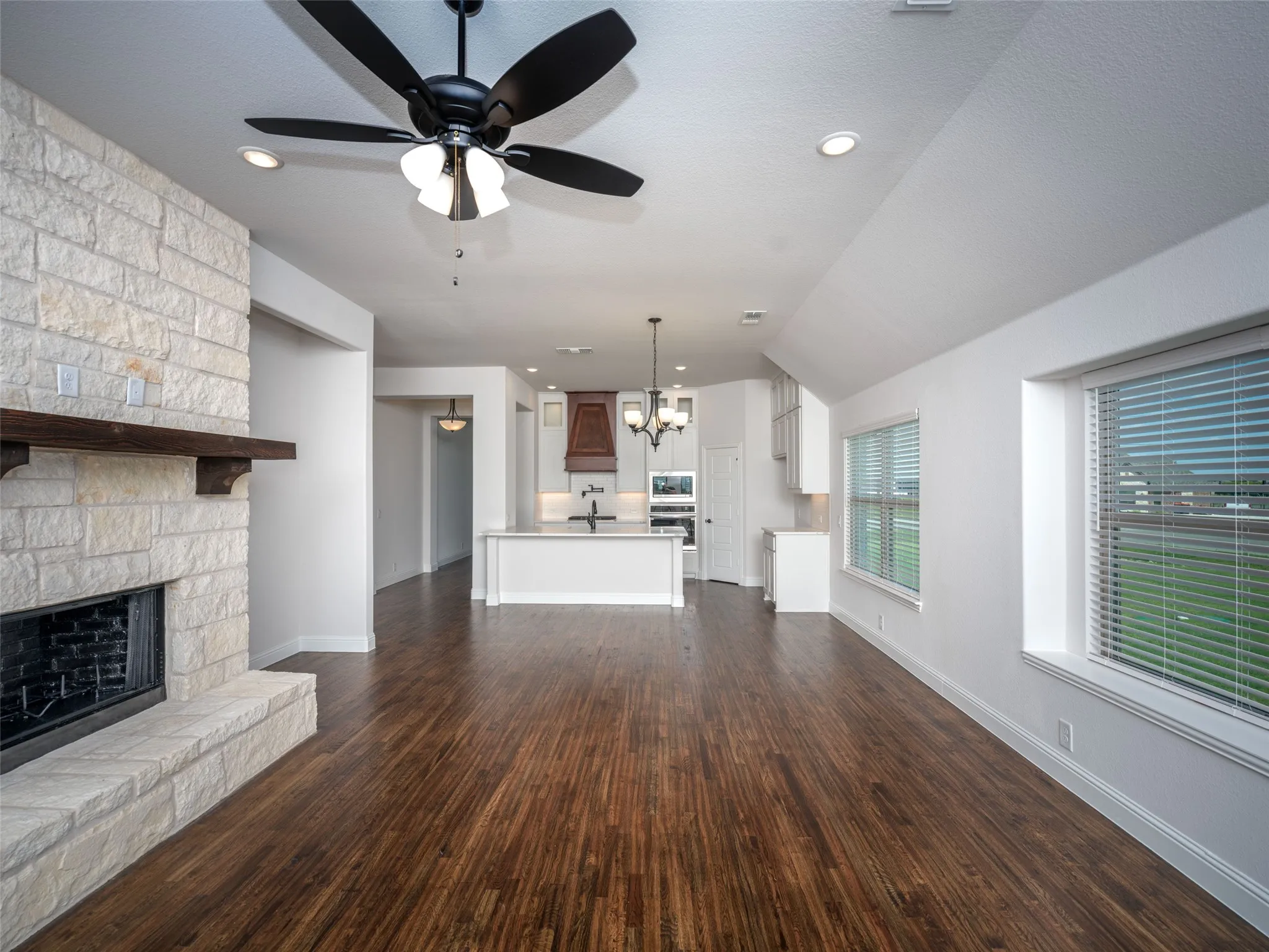 Unfurnished living room featuring a chandelier, dark wood-style flooring, recessed lighting, a fireplace, and ceiling fan