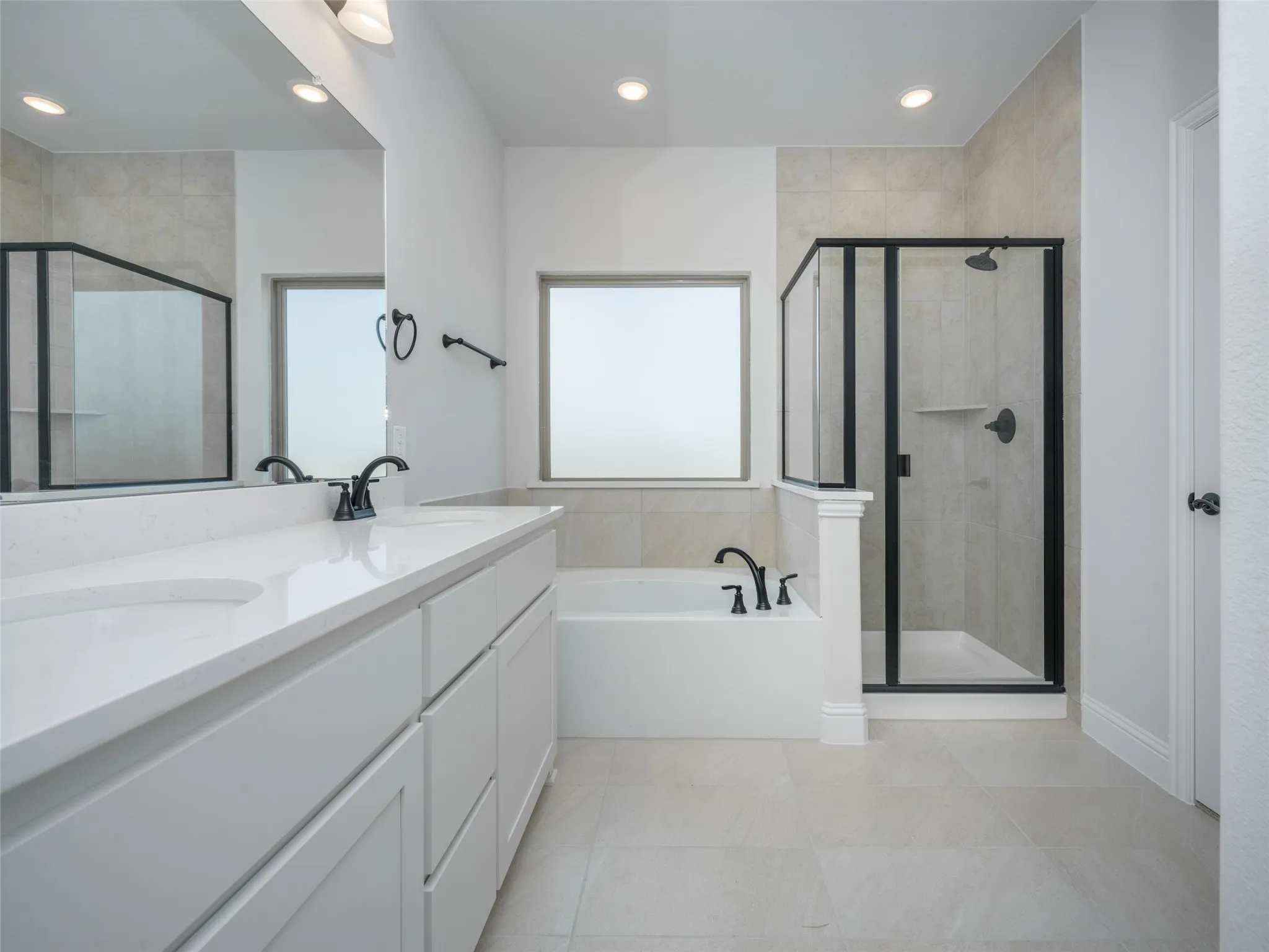 Bathroom with a bath, a shower stall, double vanity, light tile patterned floors, and recessed lighting