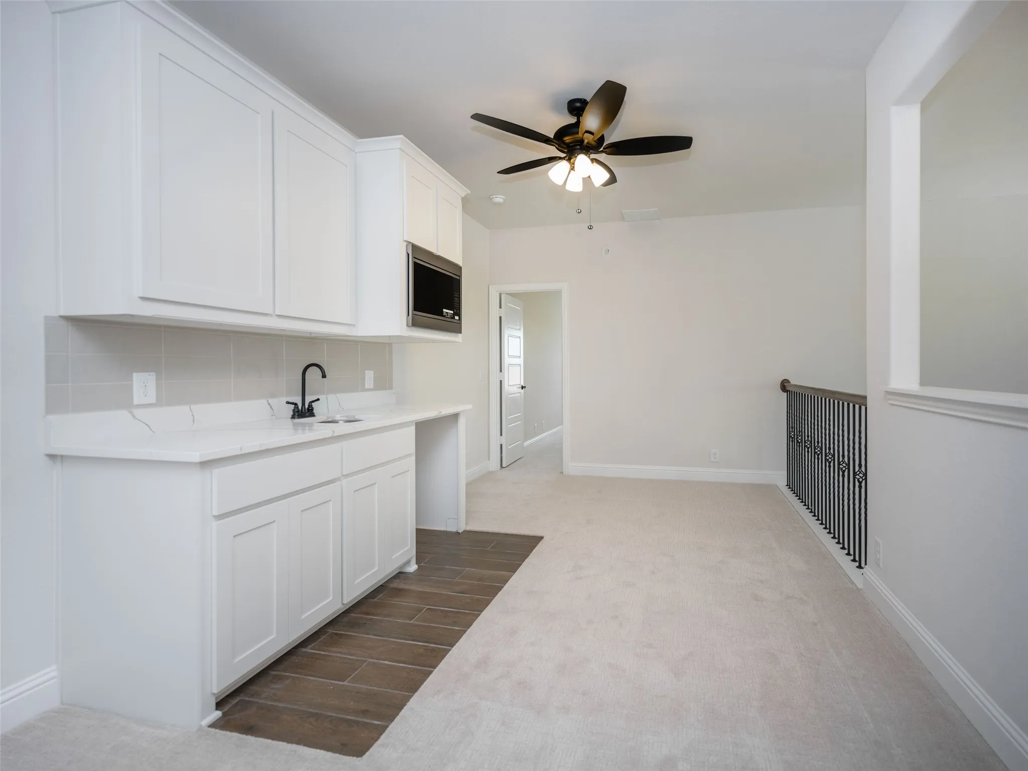 Kitchen with white cabinetry, light colored carpet, decorative backsplash, light stone counters, and ceiling fan
