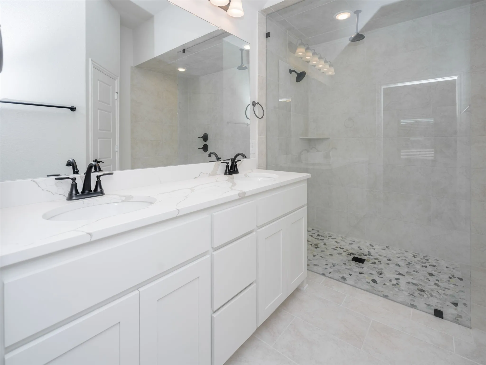 Full bathroom featuring double vanity, a walk in shower, and light tile patterned flooring