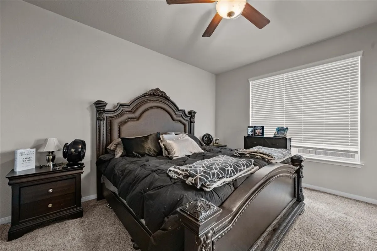 Carpeted bedroom featuring baseboards and a ceiling fan