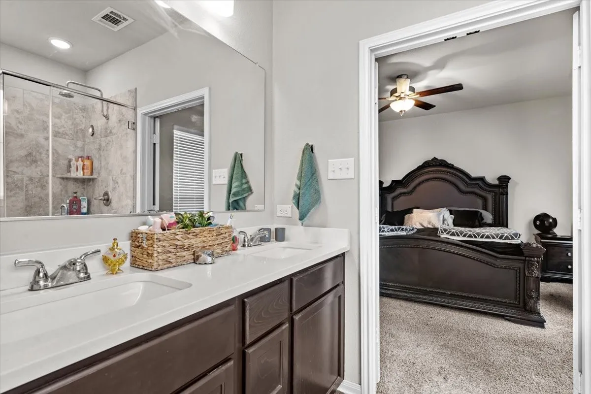 Full bathroom featuring ensuite bathroom, double vanity, tiled shower, and ceiling fan