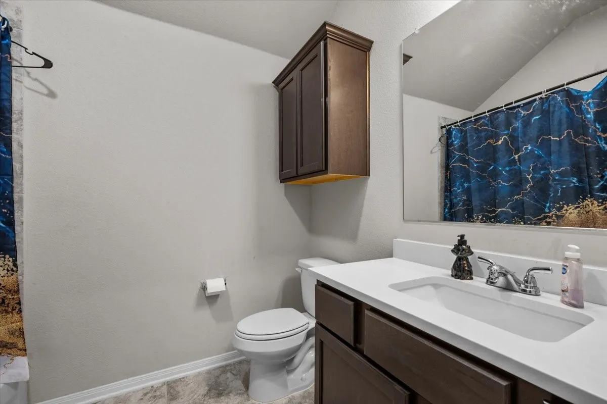 Bathroom with vanity, a textured wall, and lofted ceiling