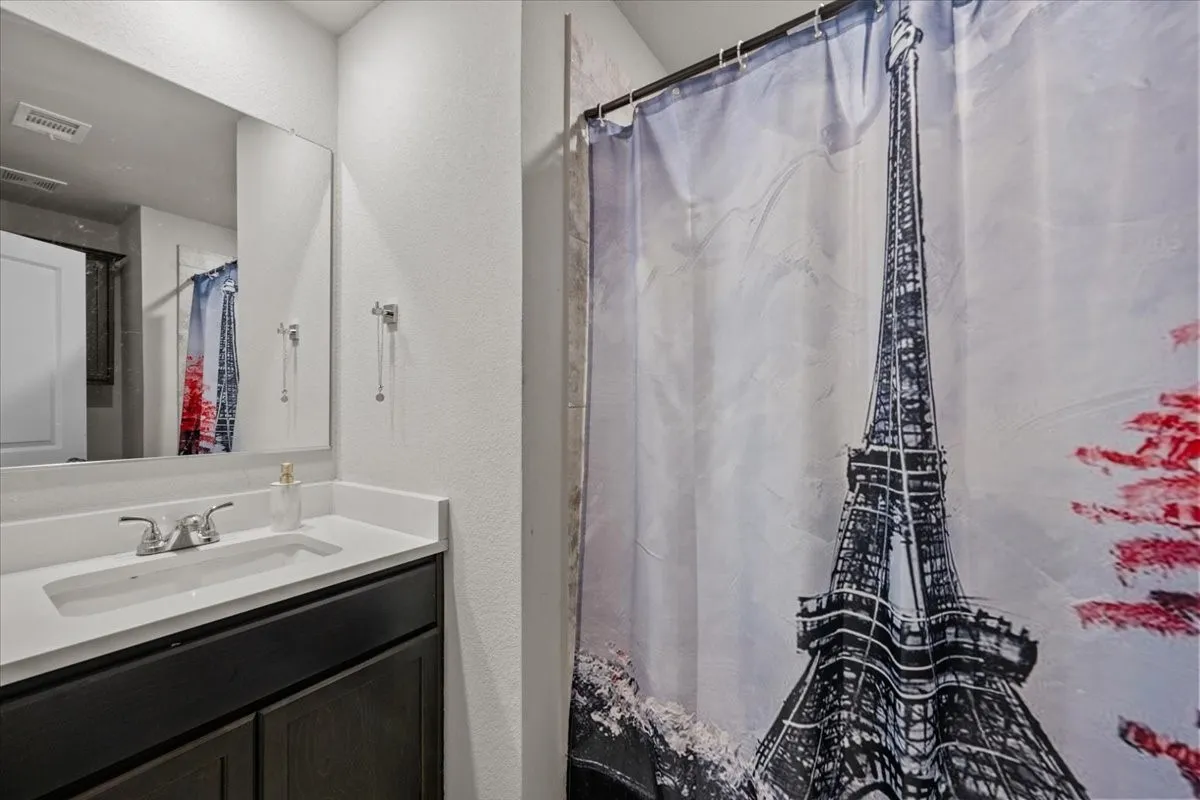 Full bathroom featuring vanity, a textured wall, and a shower with shower curtain