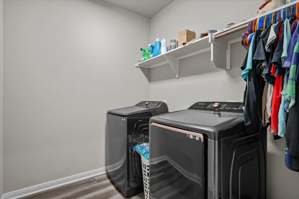 Laundry area with separate washer and dryer and wood finished floors