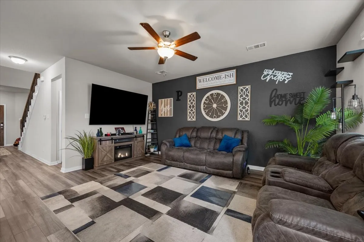 Living area with stairway, wood finished floors, and ceiling fan