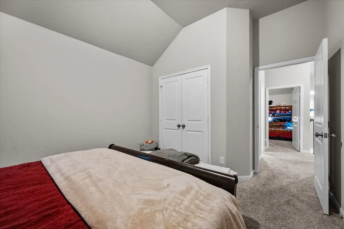Bedroom featuring vaulted ceiling, light carpet, and a closet
