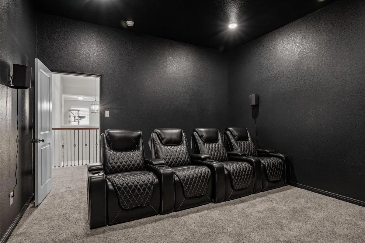 Home theater room featuring carpet flooring and a textured wall