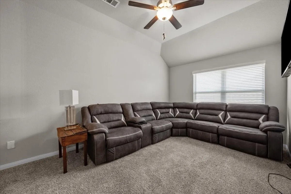 Living area featuring carpet, lofted ceiling, and a ceiling fan